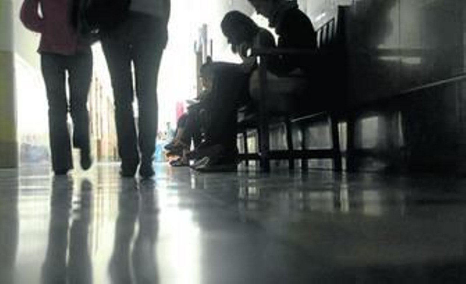 Alumnos de la Universidad de Granada aguardan en un pasillo a que llegue el profesor para una tutoría.