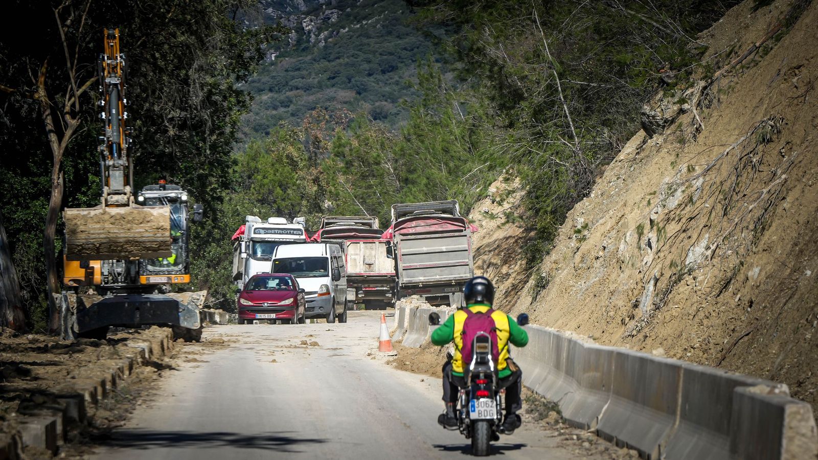 Vehículos pasando entre la maquinaria en uno de los taludes más dañados