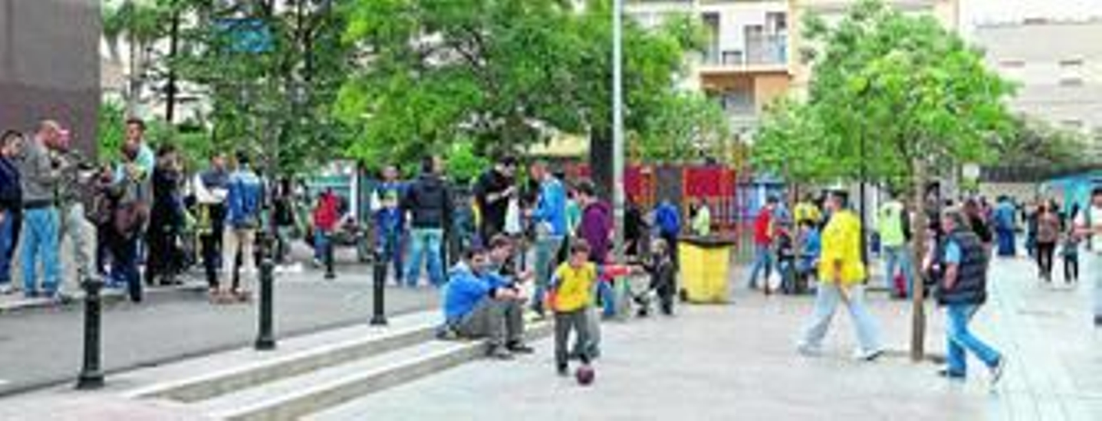 Un niño juega con un balón mientras que algunos jóvenes consumen bebidas alcohólicas a pocos metros ayer por la tarde.