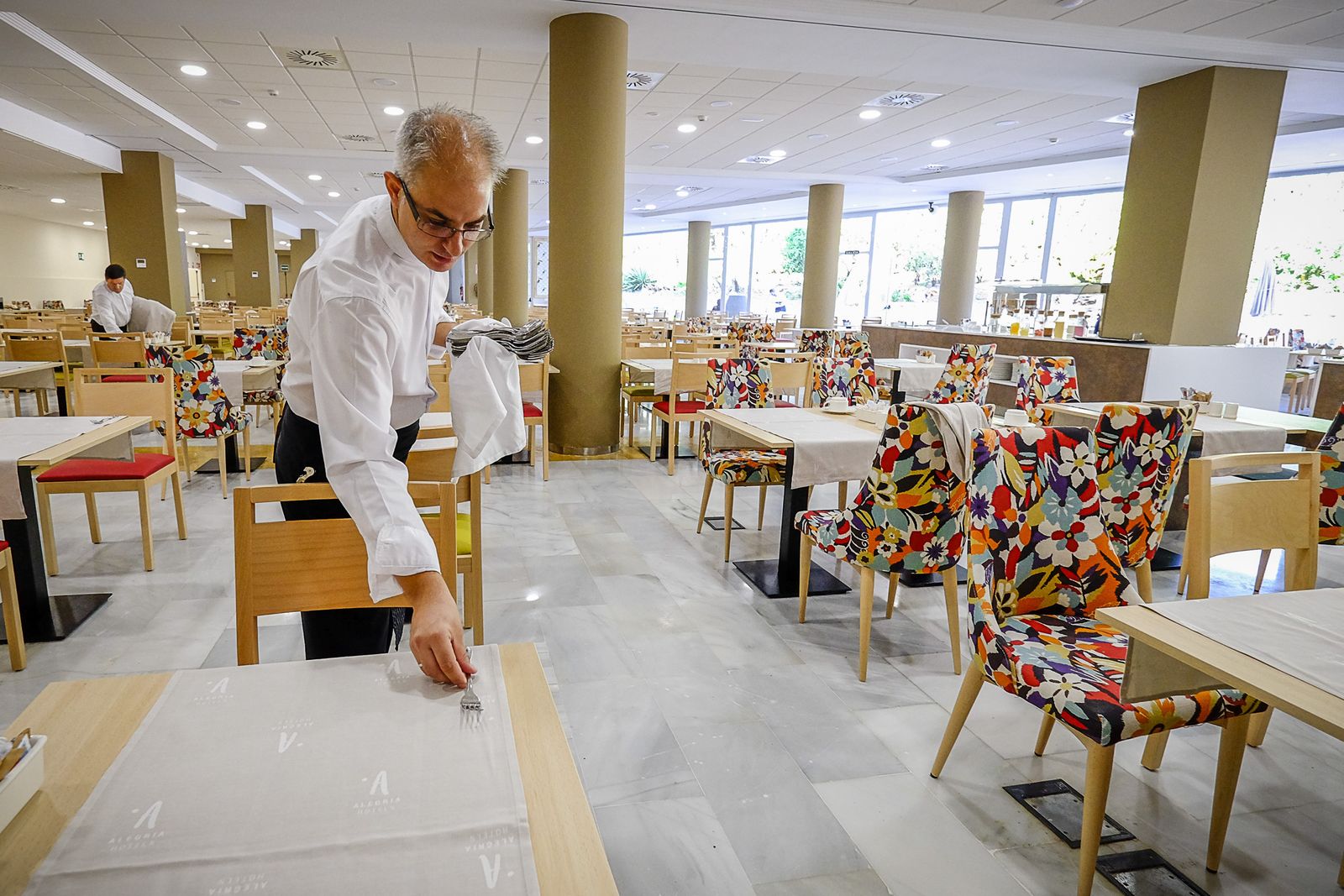 Un camarero viste una mesa en la zona de buffet del hotel Alegria Costa Ballena.