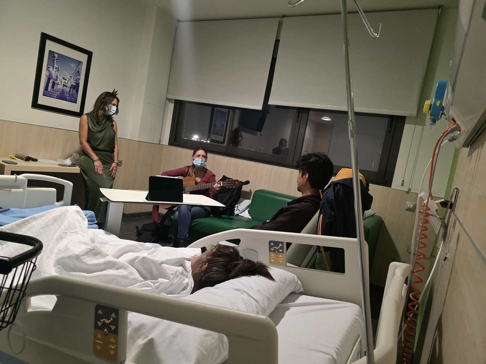 La cantante toca una pieza a la guitarra ante una paciente.