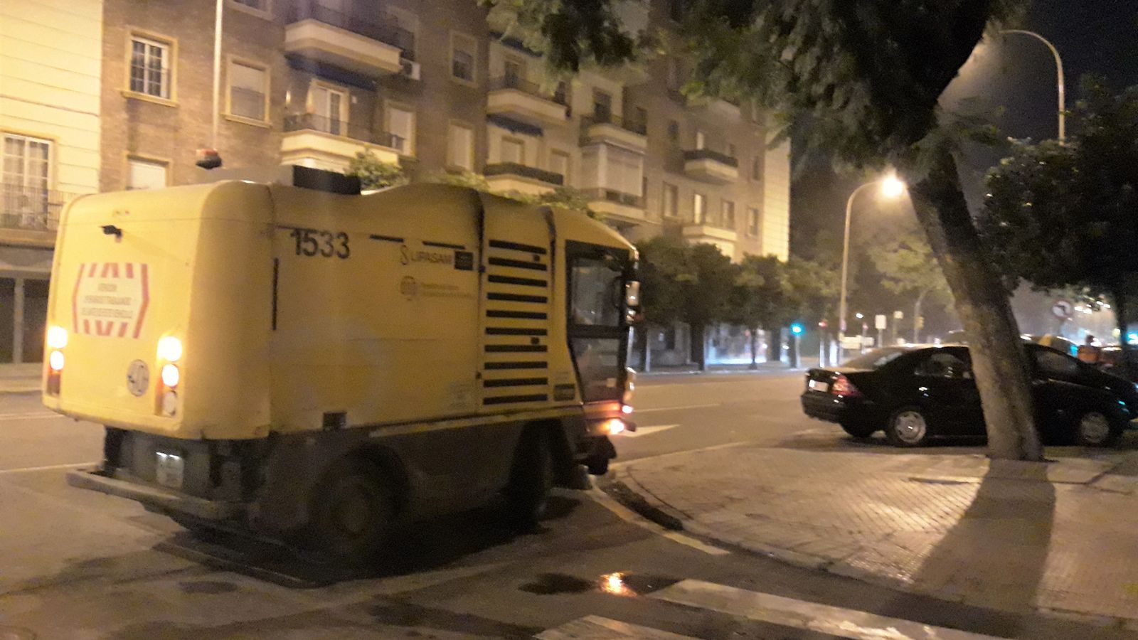 Una máquina de las amarillas aspira basura por el borde de la calzada en Los Remedios.