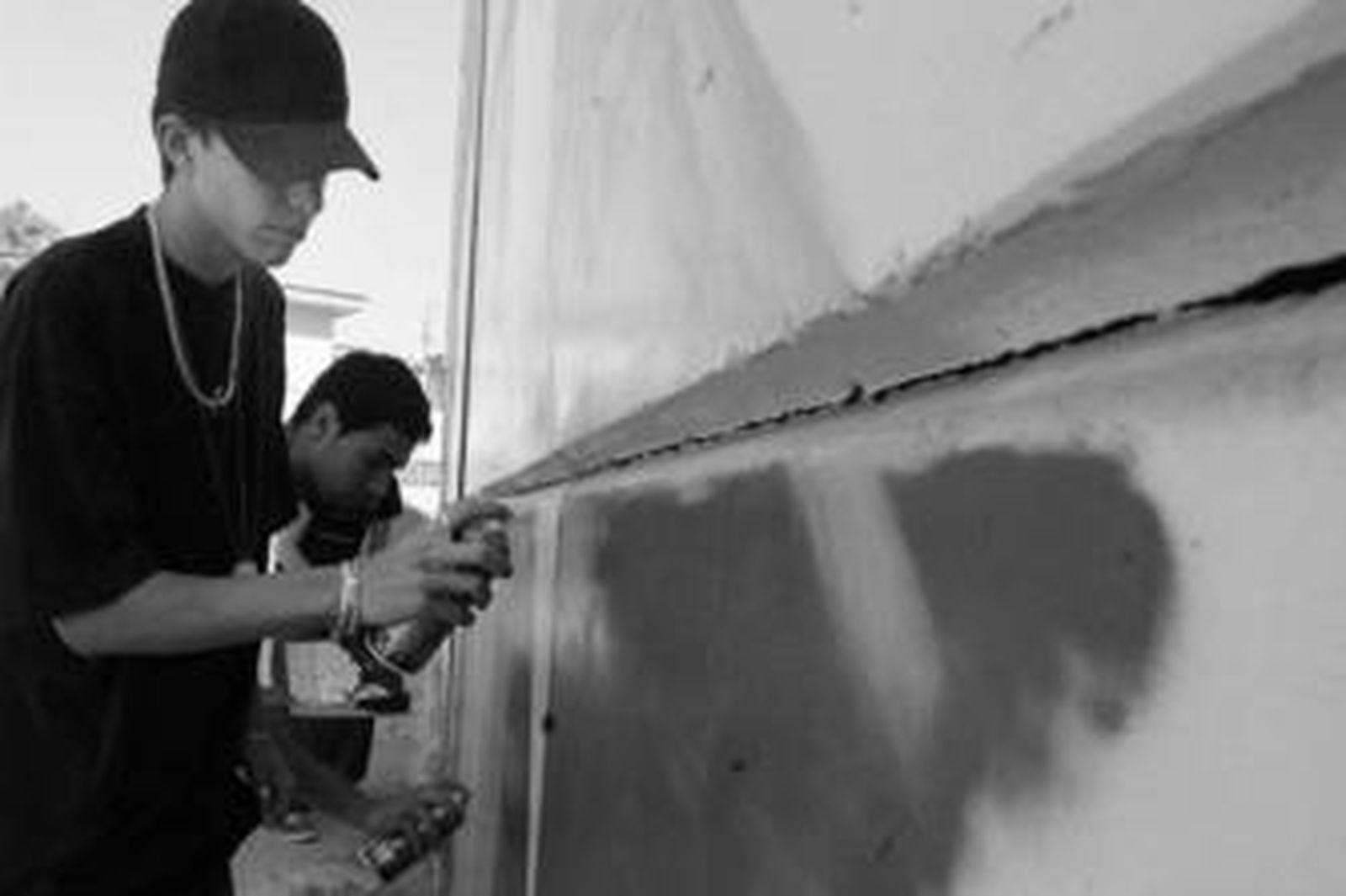 Varios jóvenes decoran una pared gracias a su habilidad con el spray.
