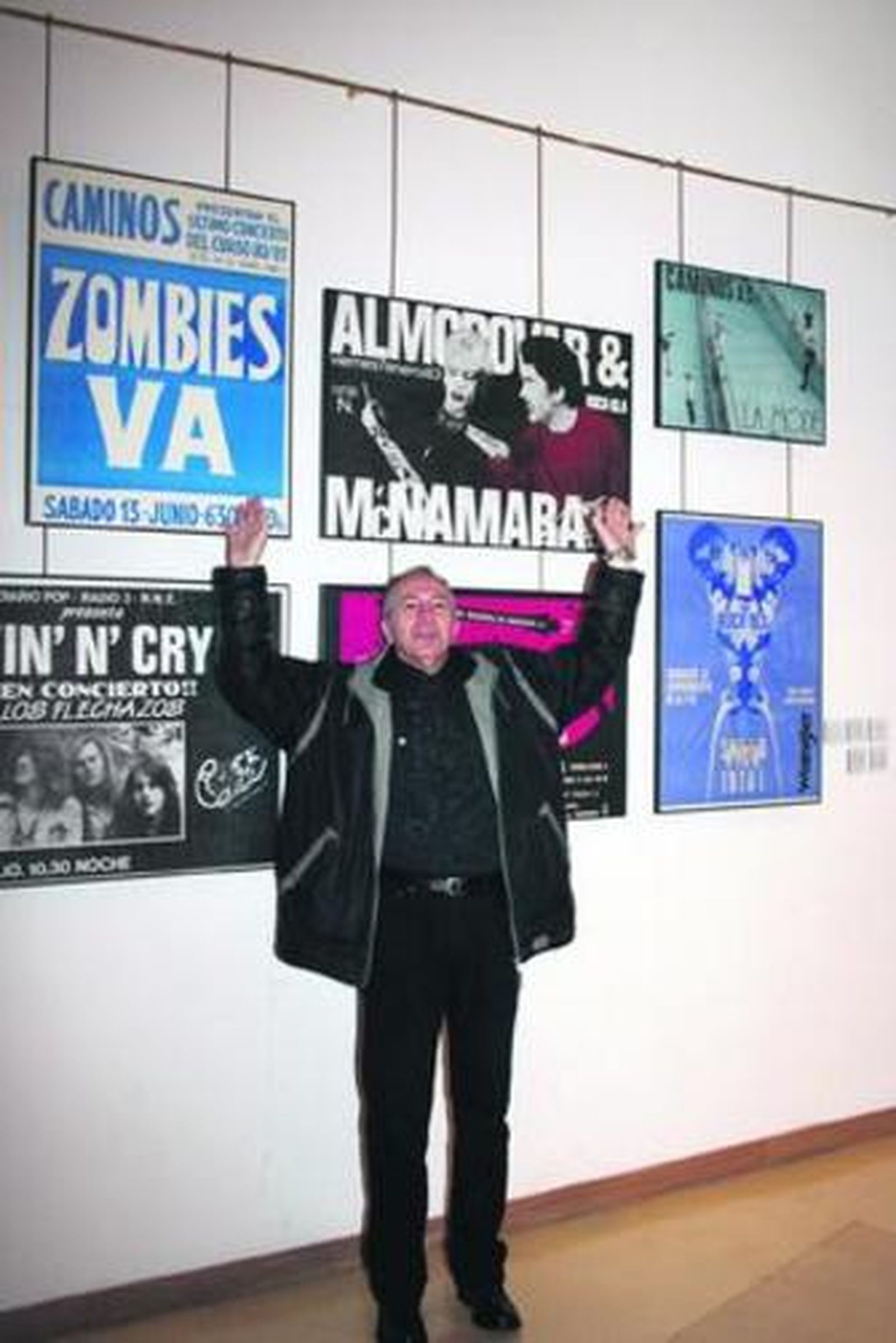 El locutor posa junto a varios de los carteles presentes en la muestra.