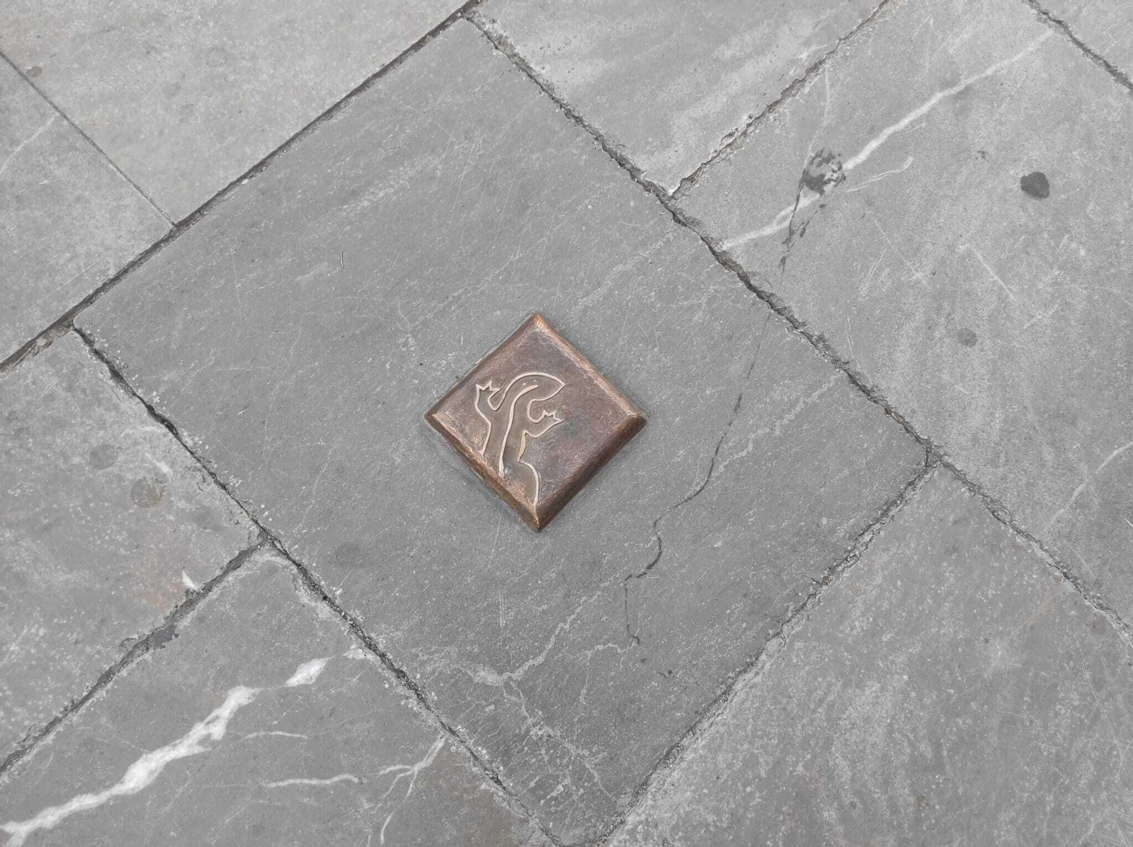 Hito de bronce del recorrido del Lagarto de la Malena junto a los Baños Árabes de Jaén.