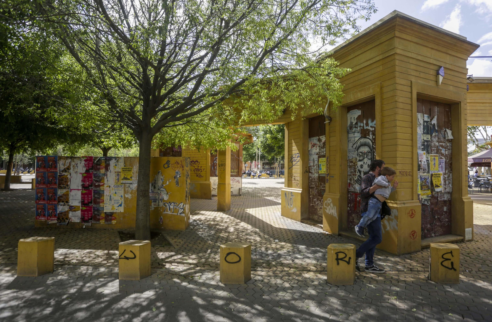 Uno de los quioscos y diverso mobiliario urbano de la Alameda de Hércules cubierto de pintadas y carteles.