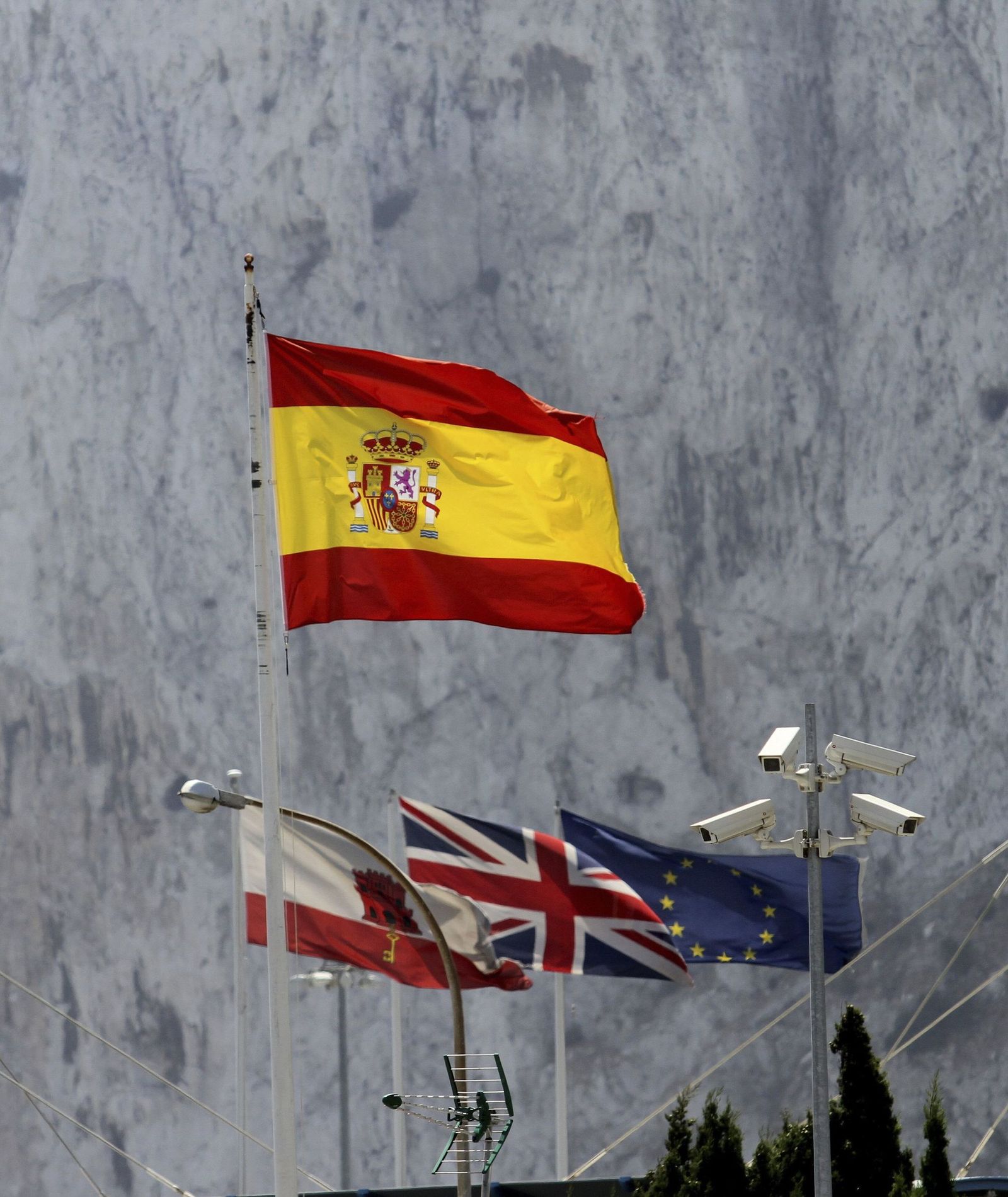 La bandera española ondea ante las de Gibraltar, Reino Unido y Unión Europea., con la pared del Peñón al fondo, en una imagen de archivo previa al Brexit.