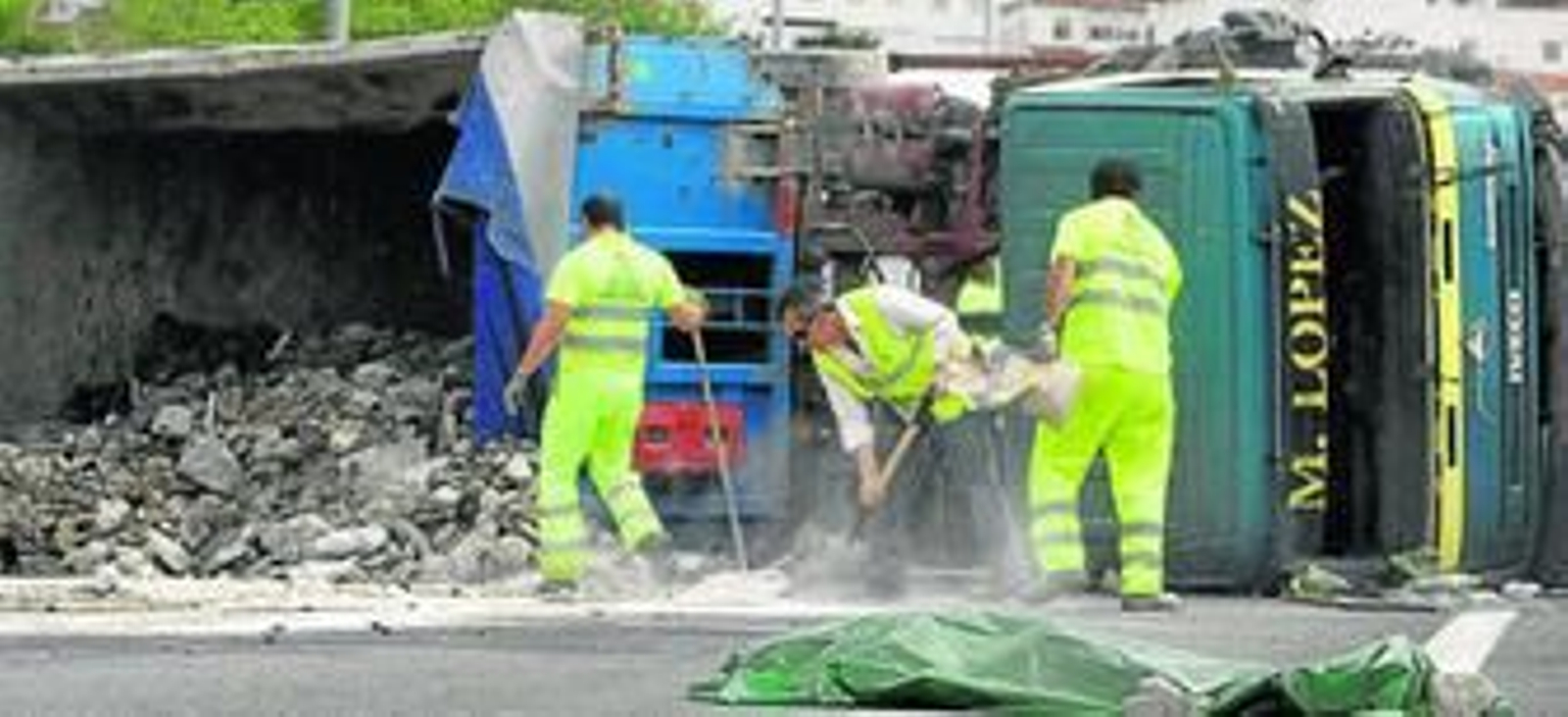 Trabajadores limpian la calzada, en la que permanece el cadáver del camionero.