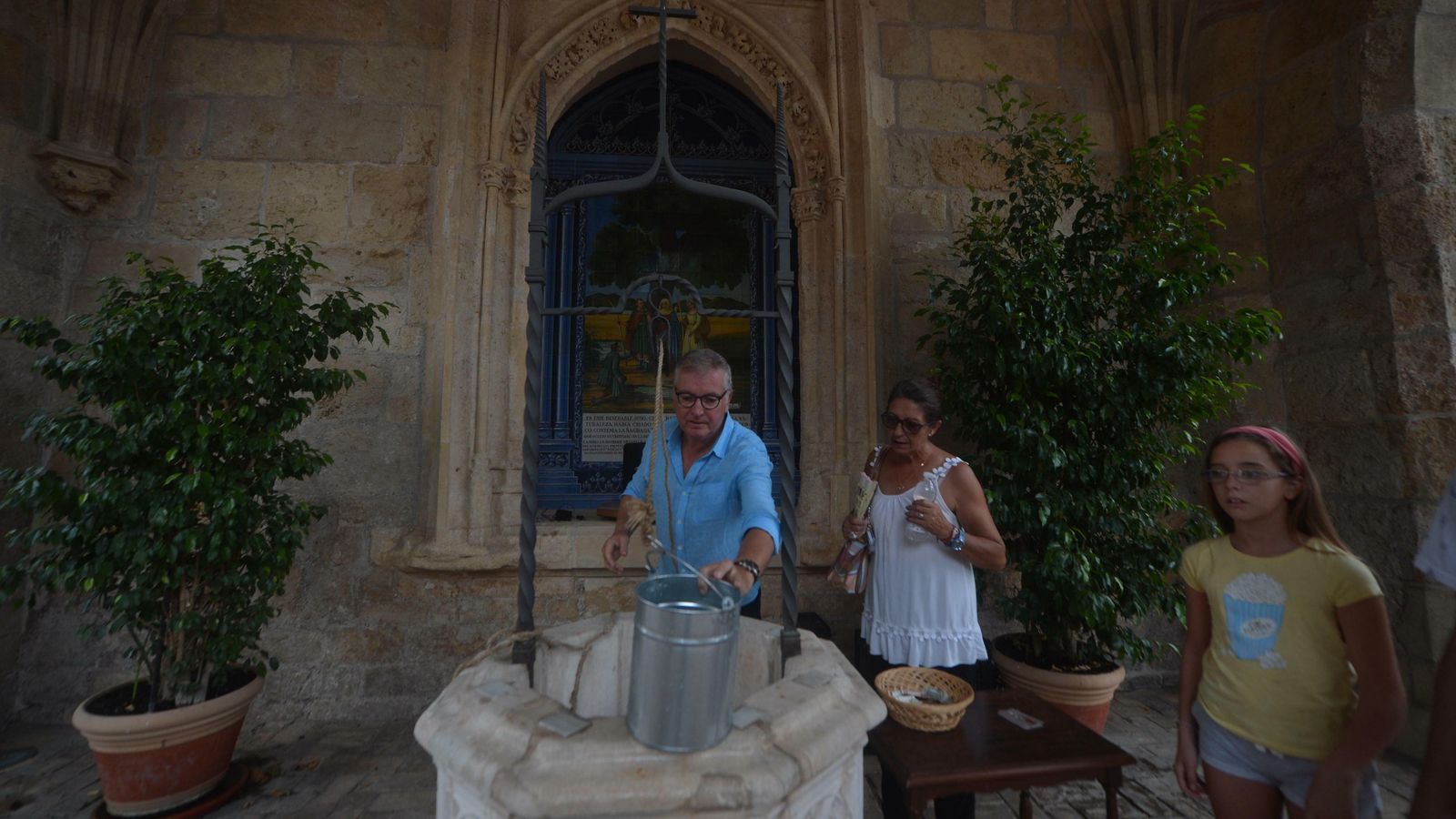 Manuel Luna llena una botella de agua que ha sacado del pocito.