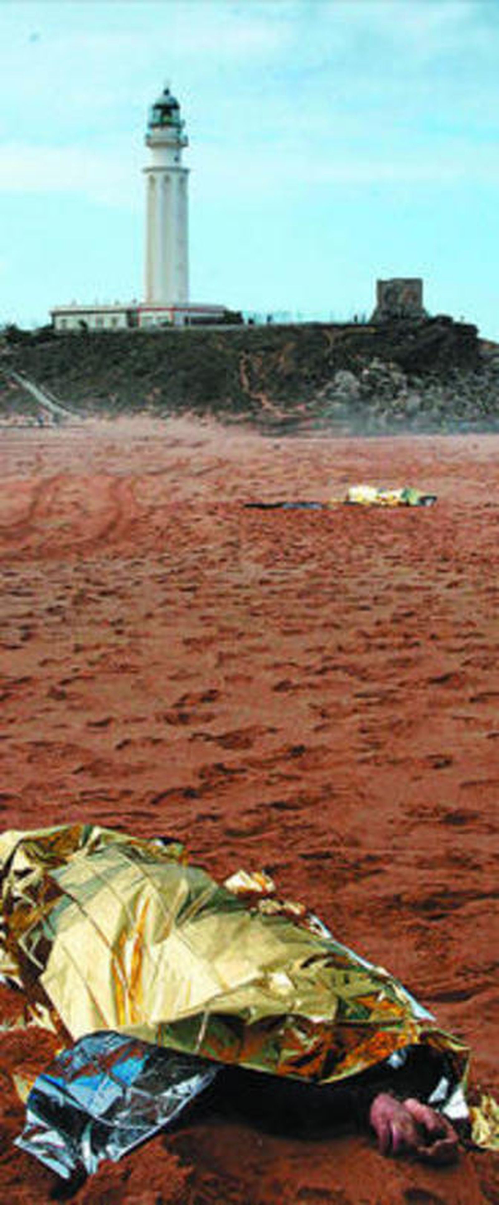 El cuerpo de dos de los fallecidos, con el faro de Trafalgar al fondo.