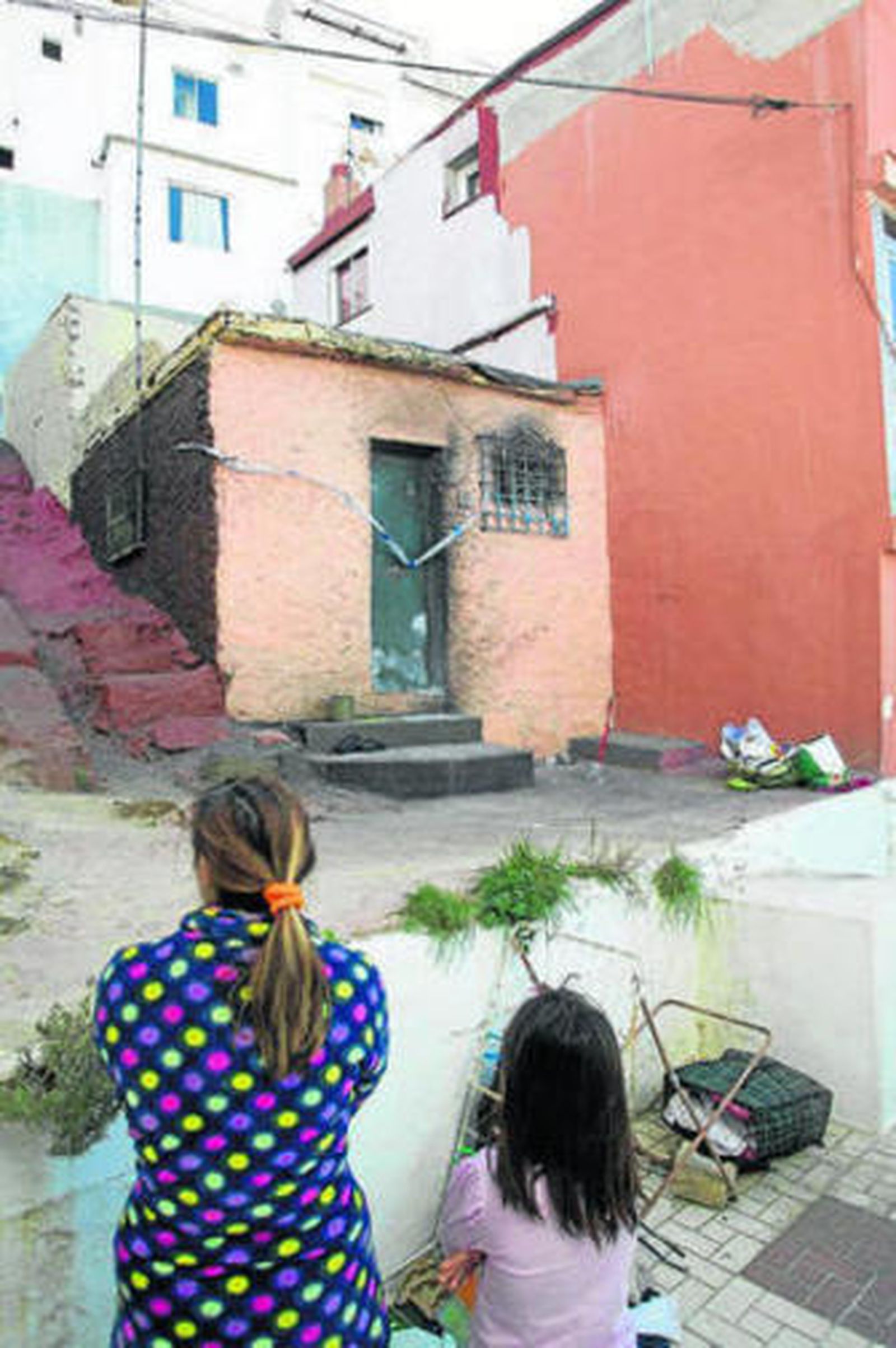 Una mujer y una niña observan la casa donde ocurrió el incendio.