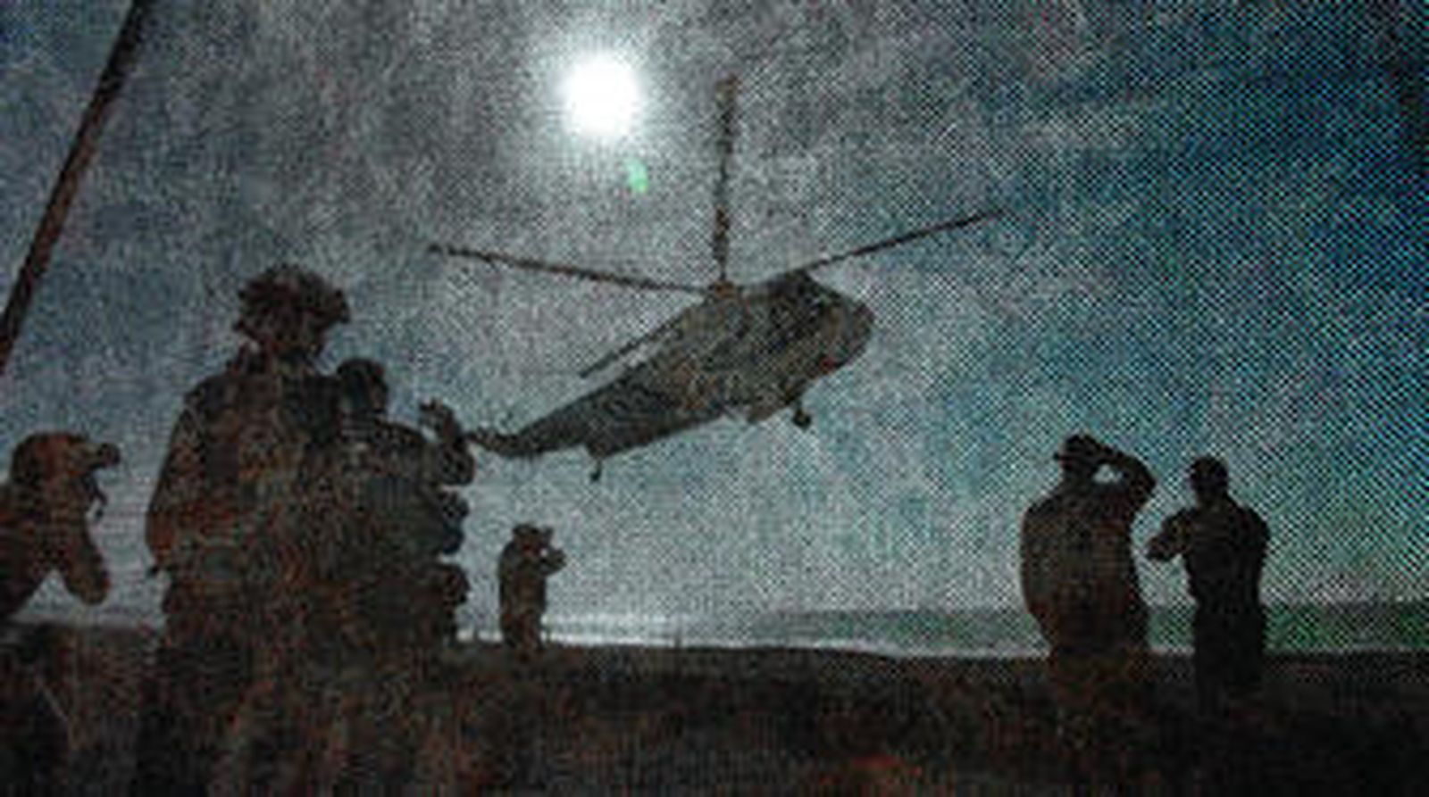 Un  helicóptero Sea King aterriza para depositar tropas en una zona asegurada por infantes de marina holandeses. La imagen está captada a través de una red mimética de camuflaje.
