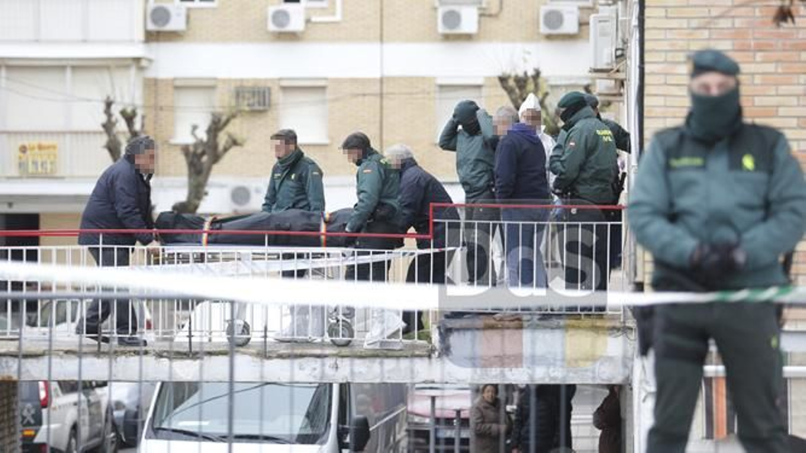Los agentes sacan el cadáver del hombre de la vivienda.