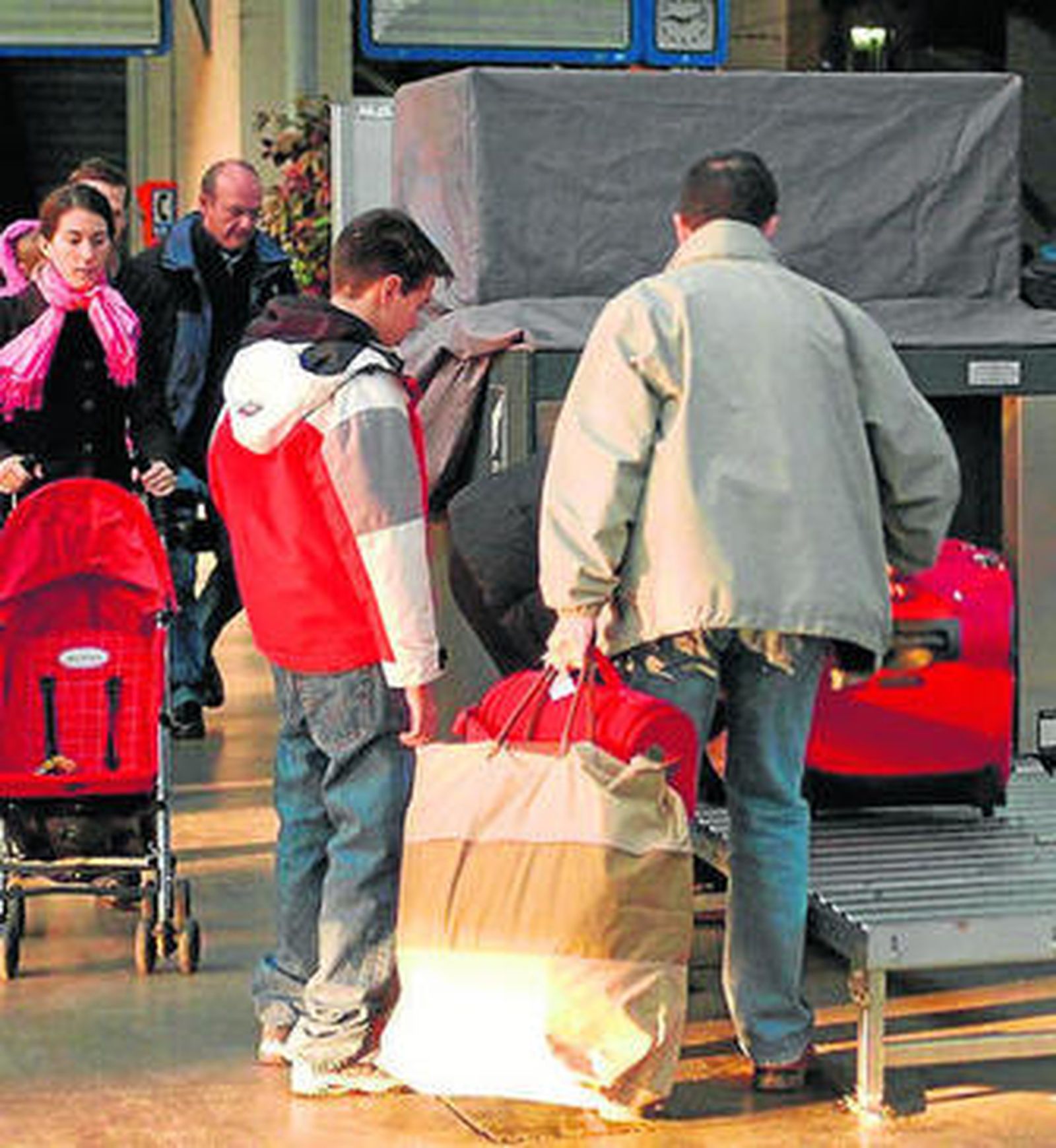 Viajeros pasando por la máquina de control su equipaje.