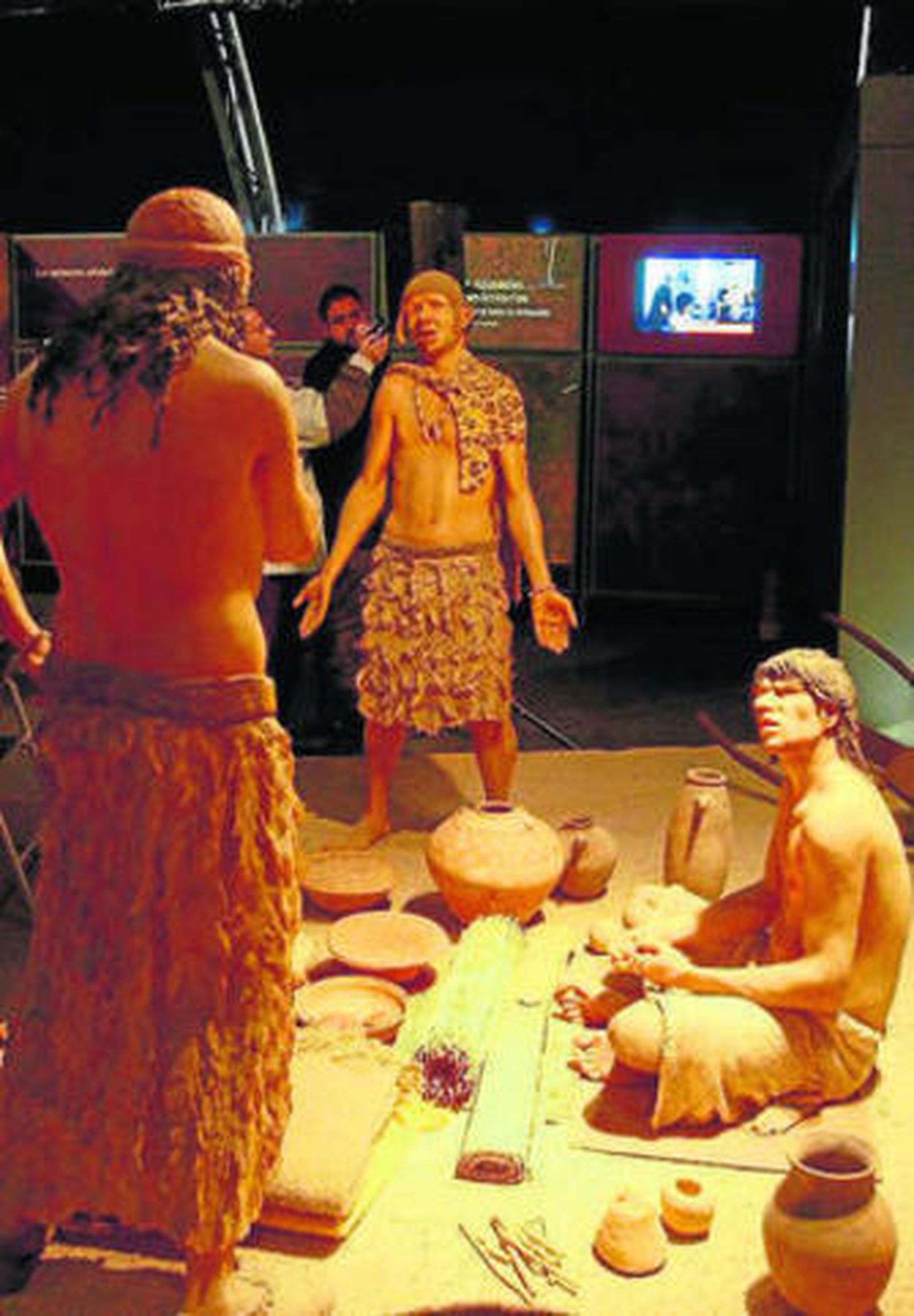 Arriba, una escena de transacción comercial de hace 5.000 años, cuando ya habían aparecido los escribas. Al lado, el alcalde y Luis Reverter (secretario general de La Caixa) hablan al fondo de una escena que representa una cabaña del poblado de Jericó.