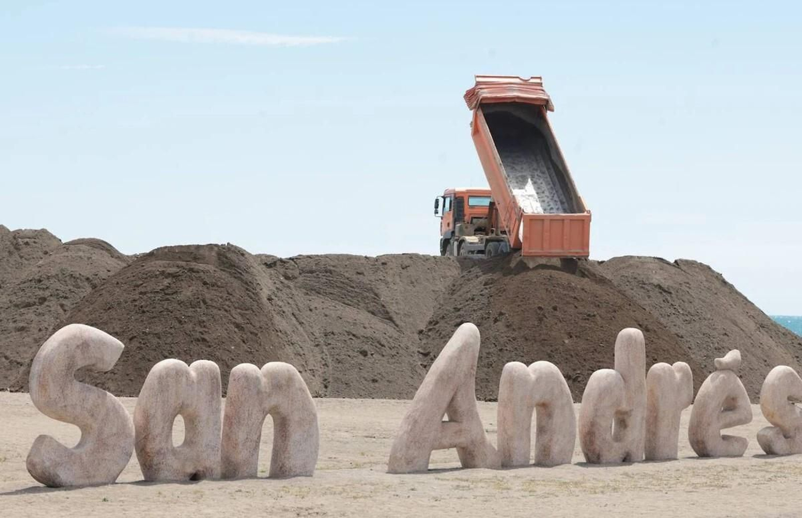 Un camión descargando arena en la playa de San Andrés.