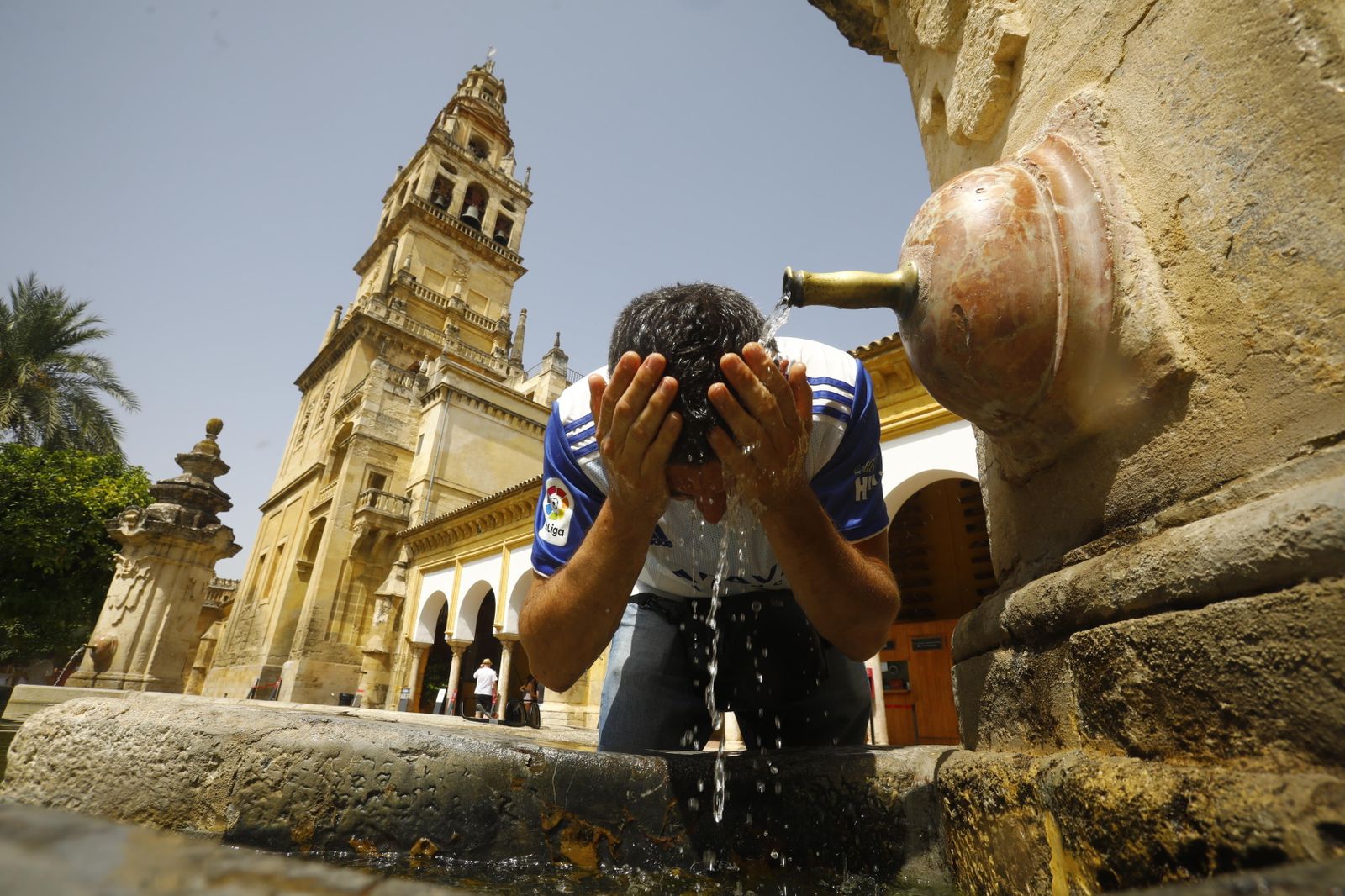 Un joven se refresca en el patio de los naranjos de la Mezquita-Catedral.