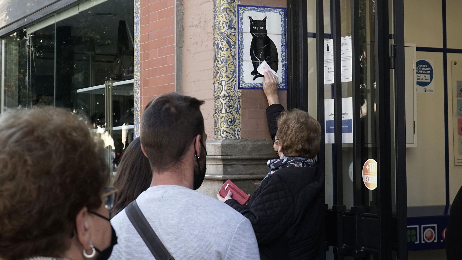 Una señora frota el décimo por el azulejo del Gato Negro.
