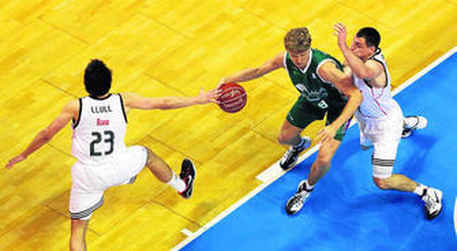 Mindaugas Kuzminskas bota el balón ante Jonas Maciulis y Sergio Llull.