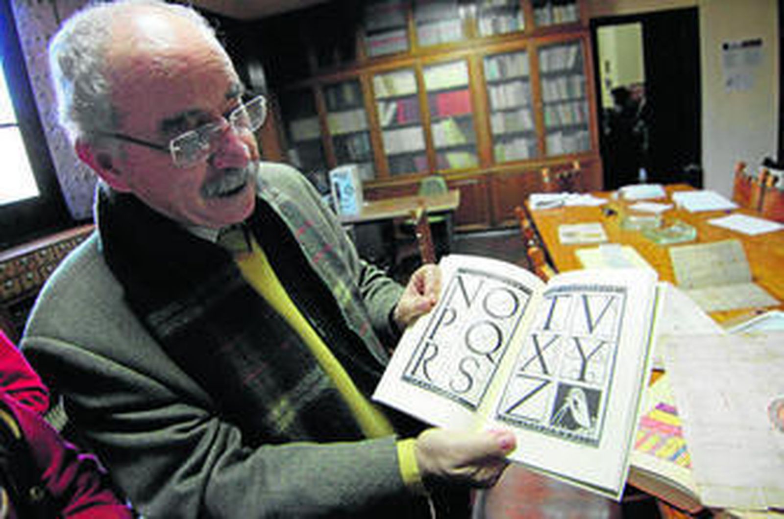 Manuel Romero muestra un libro en el que aparece un tipo de letra conocida como capital clásica.