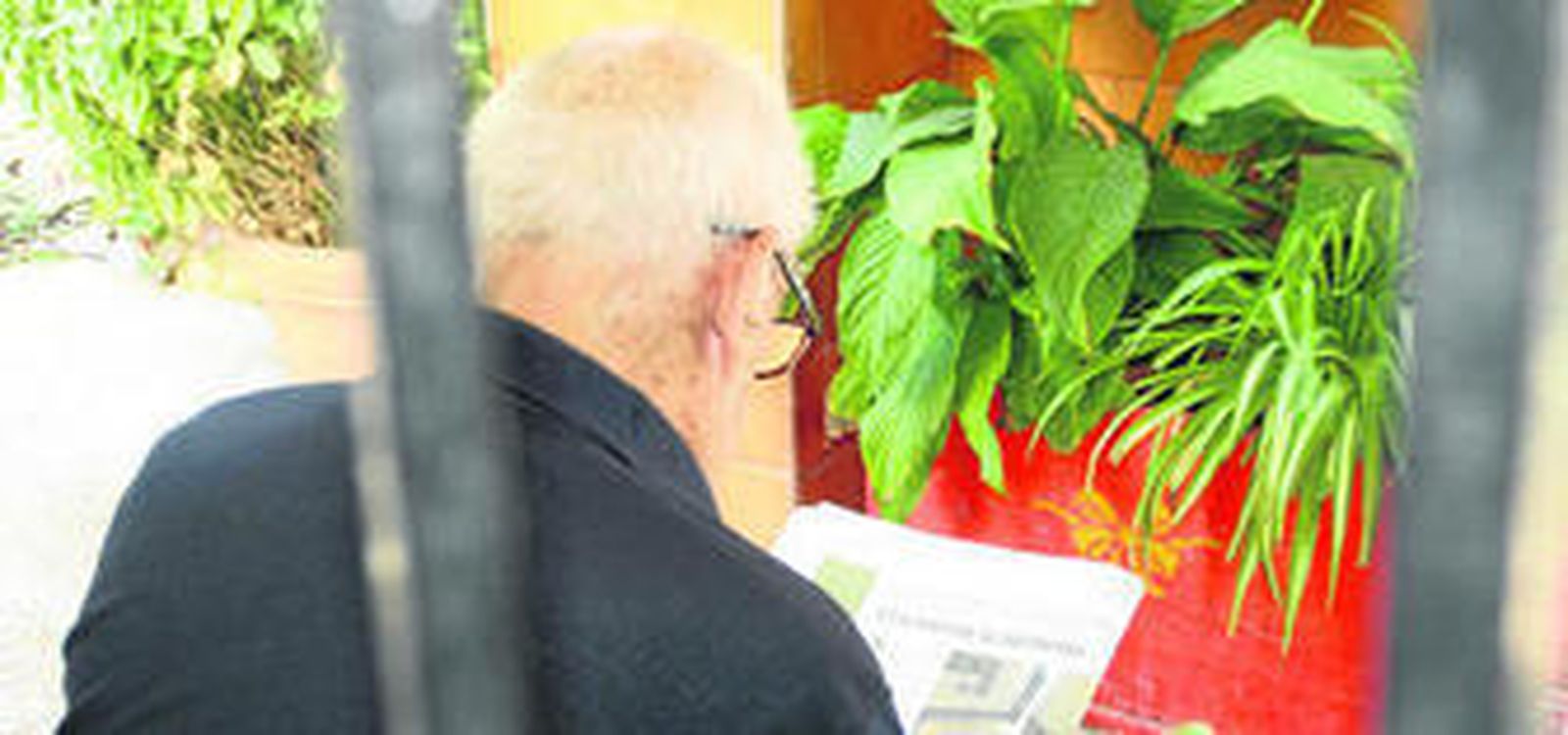 Anciano leyendo el periódico en el porche del centro residencial Aurora.