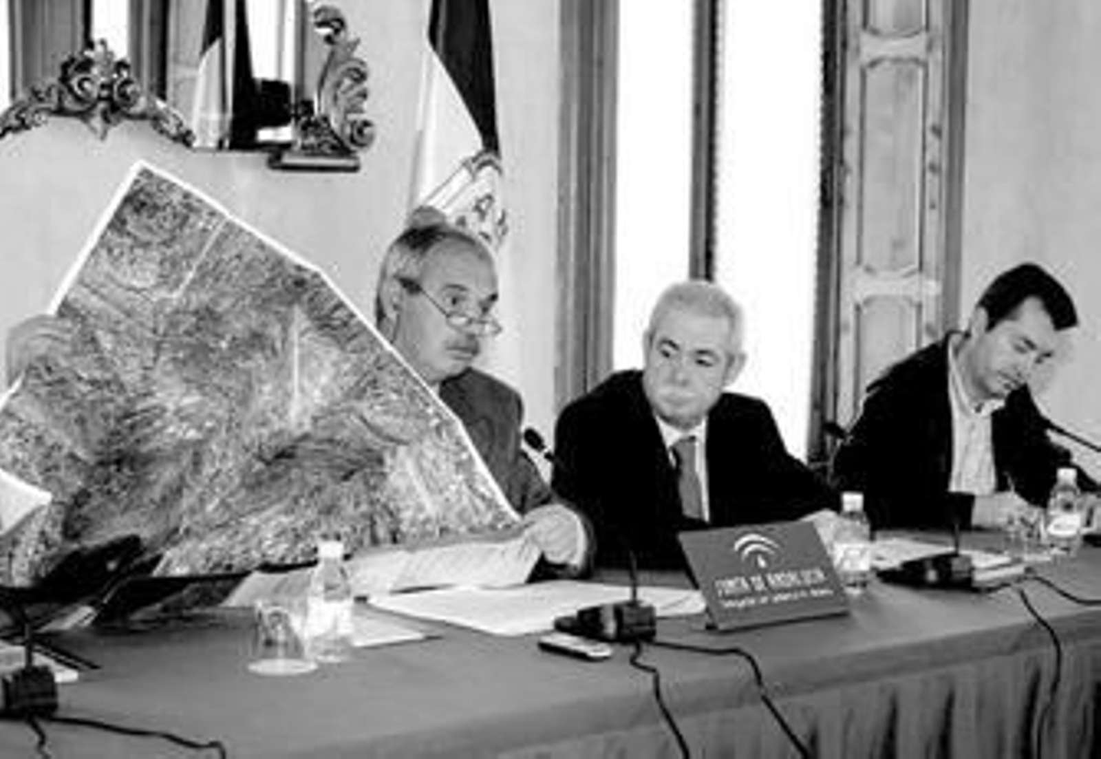 El director del Instituto de Cartografía expande el mapa para mostrárselo al delegado de Vivienda.