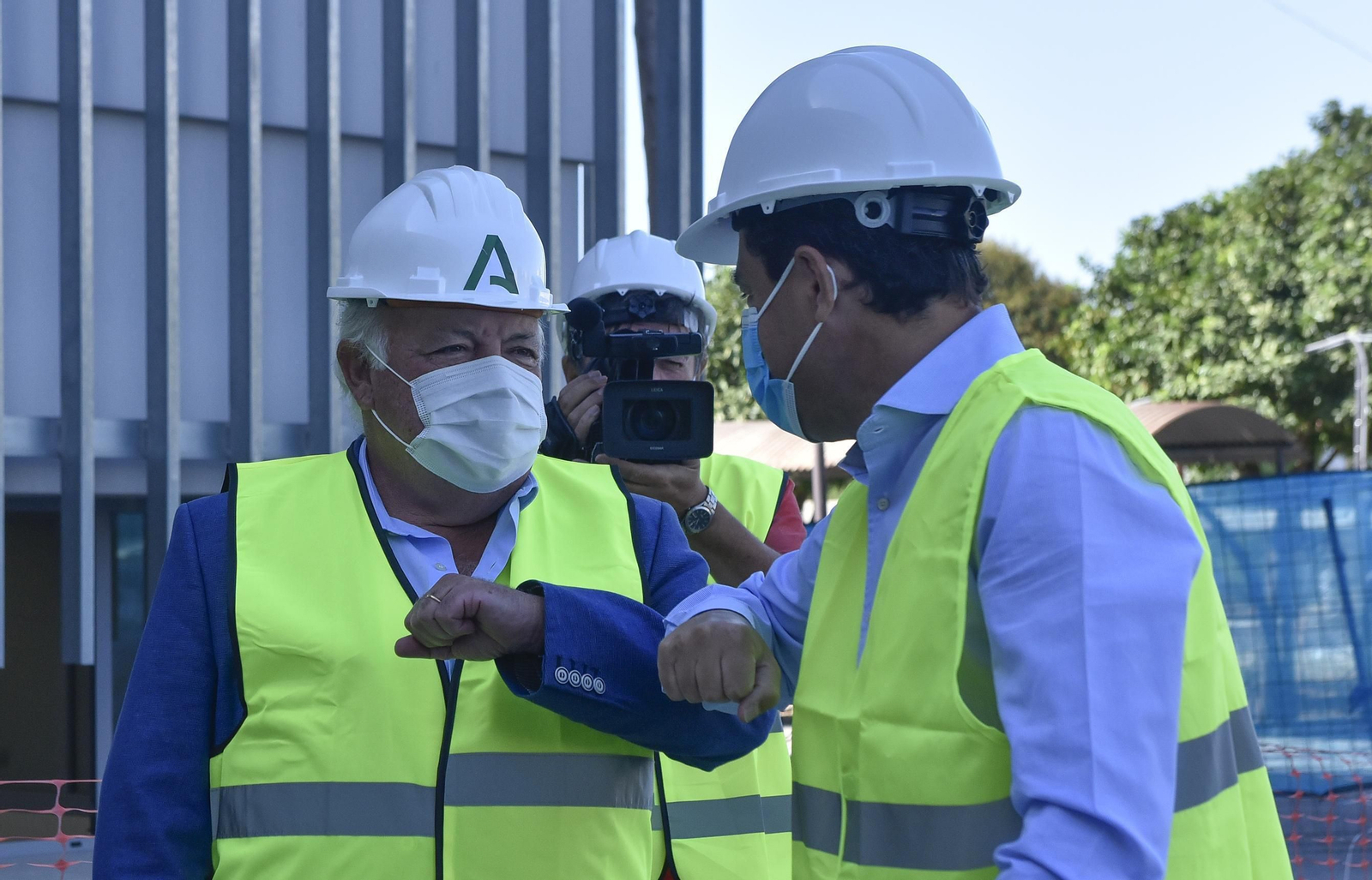 Juanma Moreno choca el codo con el consejero de Salud, Jesús Aguirre, durante una visita a las obras del Hospital Militar.