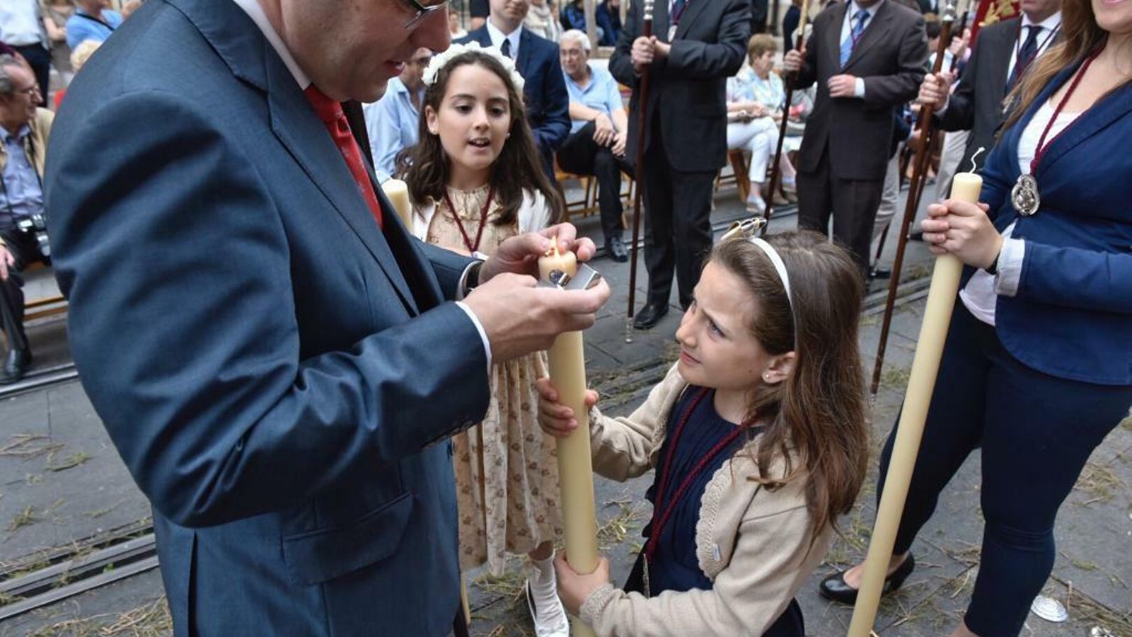 Un diputado de tramo enciende el cirio de una niña en la procesión del Corpus.