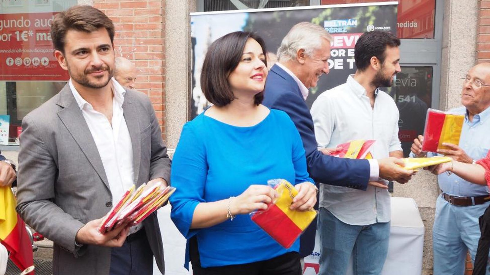 Beltrán Pérez y Virginia Pérez, con Javier Arenas al fondo, con las banderas en la mano.