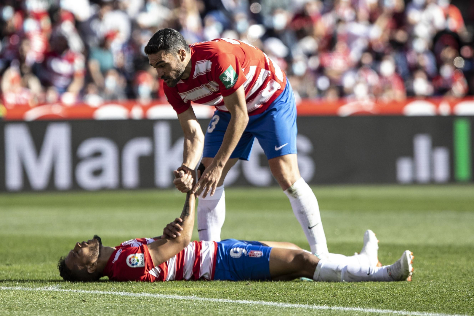Jorge Molina ayuda a Luis Suárez a levantarse en el Estadio Nuevo Los Cármenes.