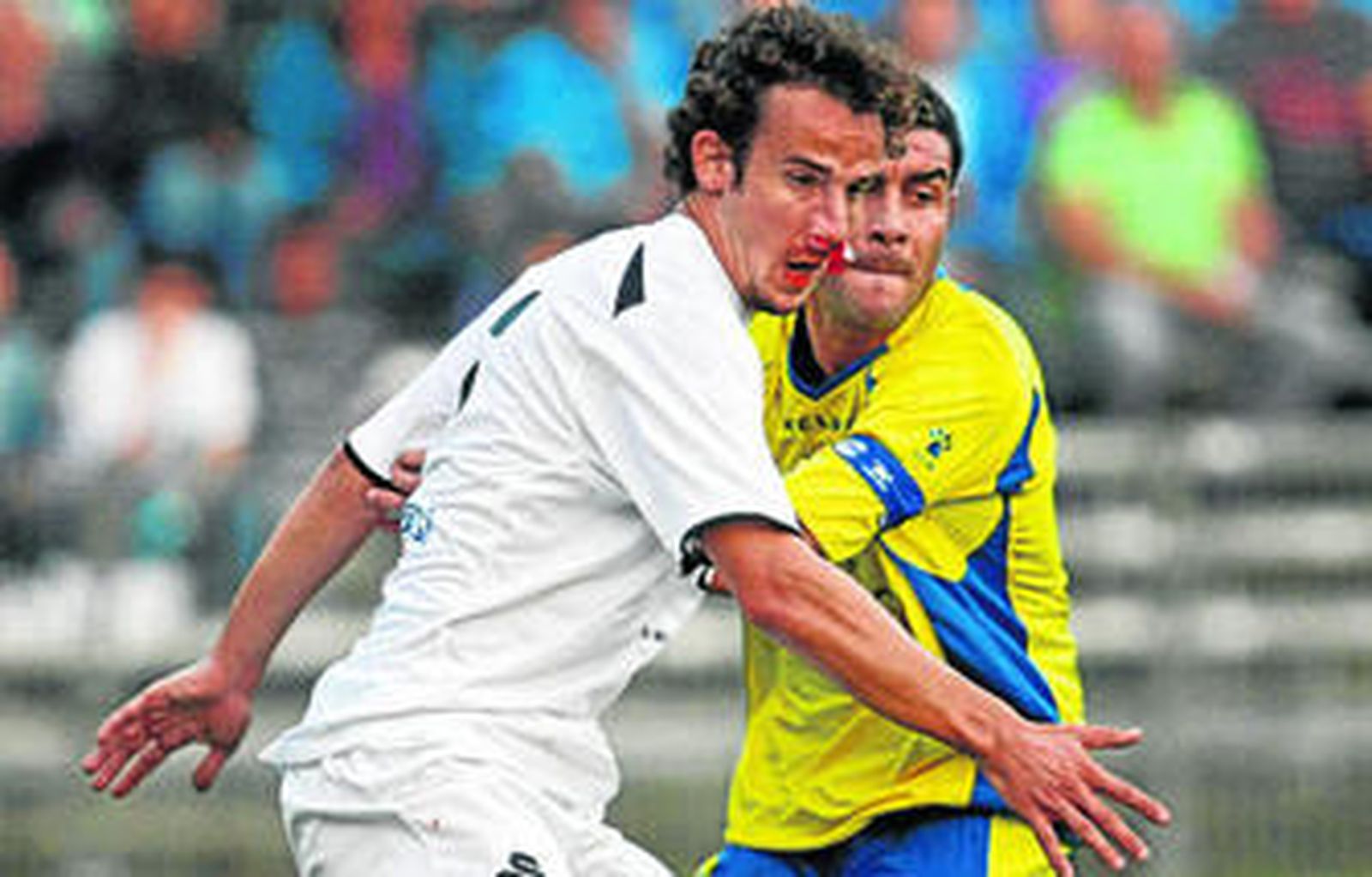 Enrique (d) pugna con un jugador visitante que sangra por la nariz en el último Cádiz-Ceuta.