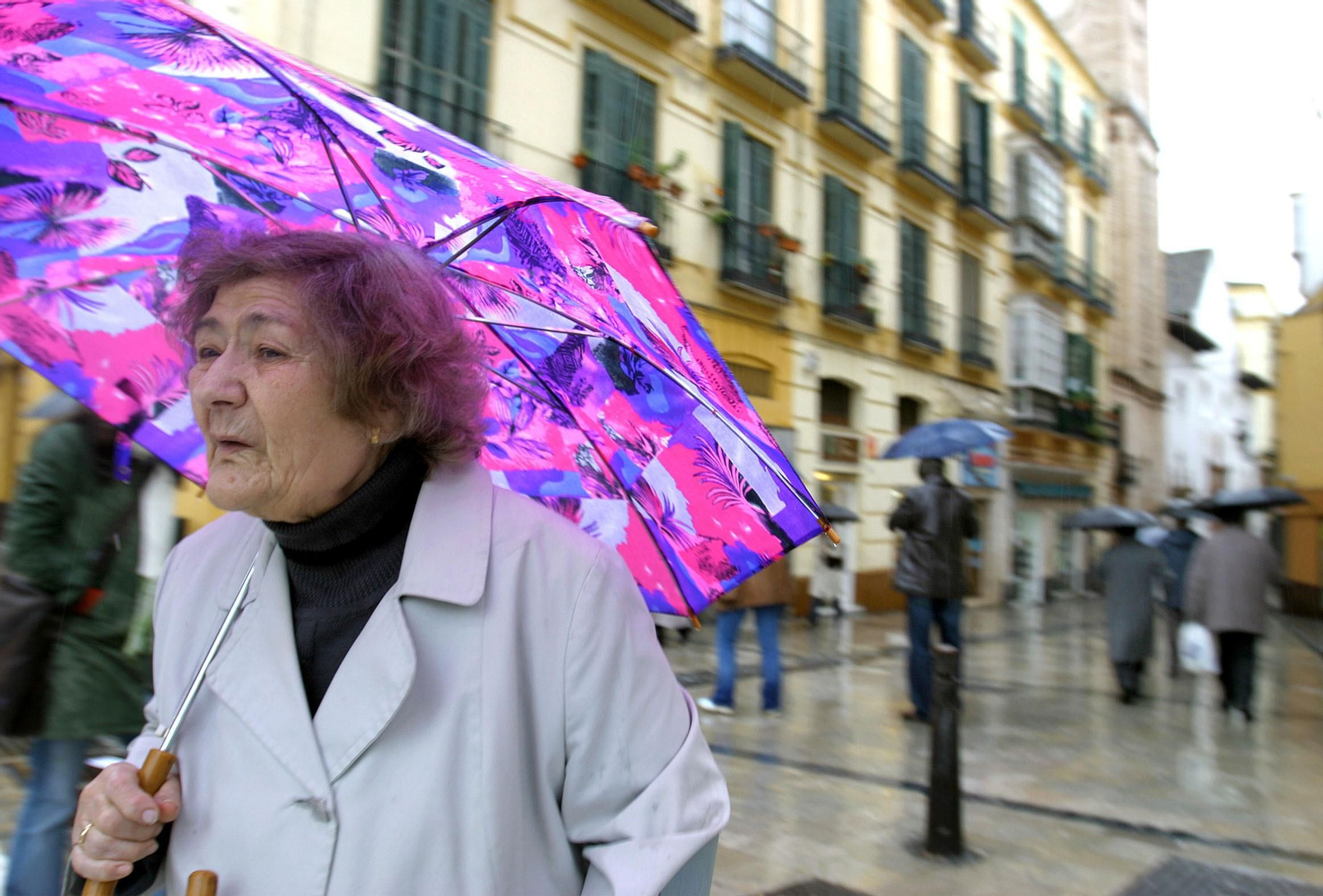 Una mujer se protege de la lluvia con su paraguas.