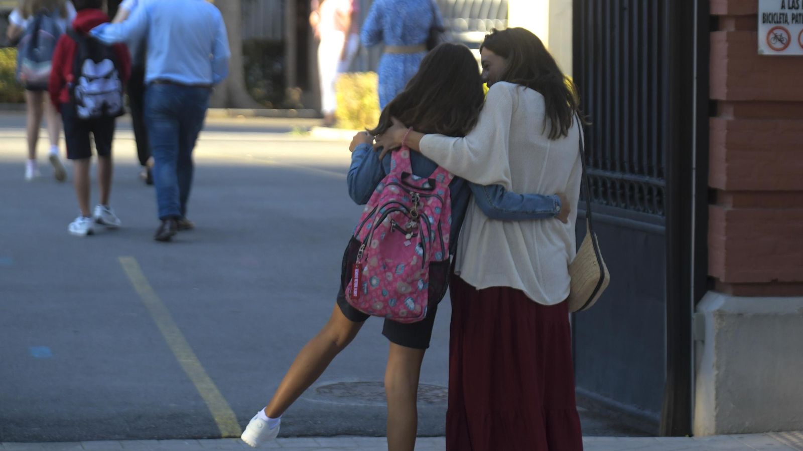 Una madre se despide de su hija en la puerta del colegio