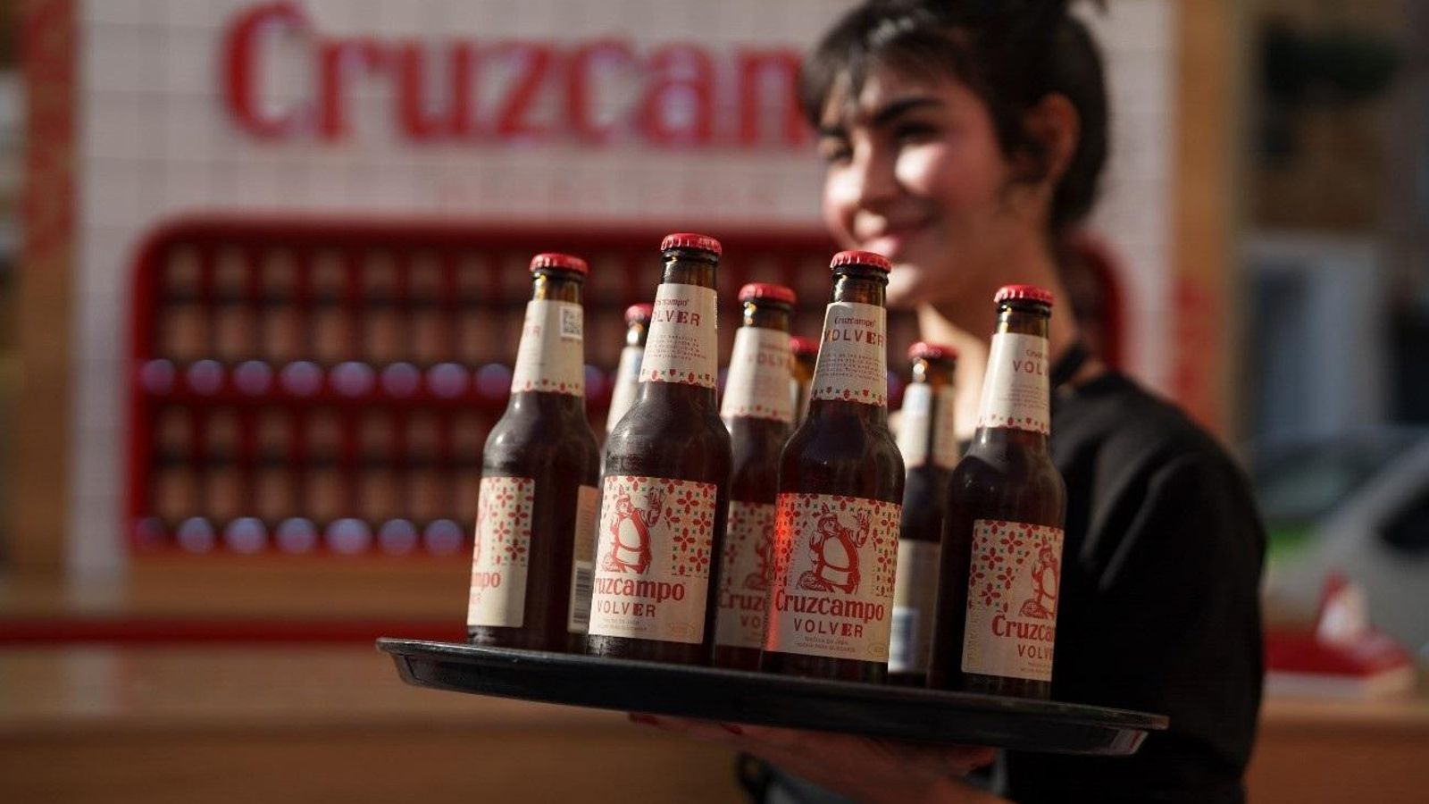 Una camarera con varios botellines de Cruzcampo Volver