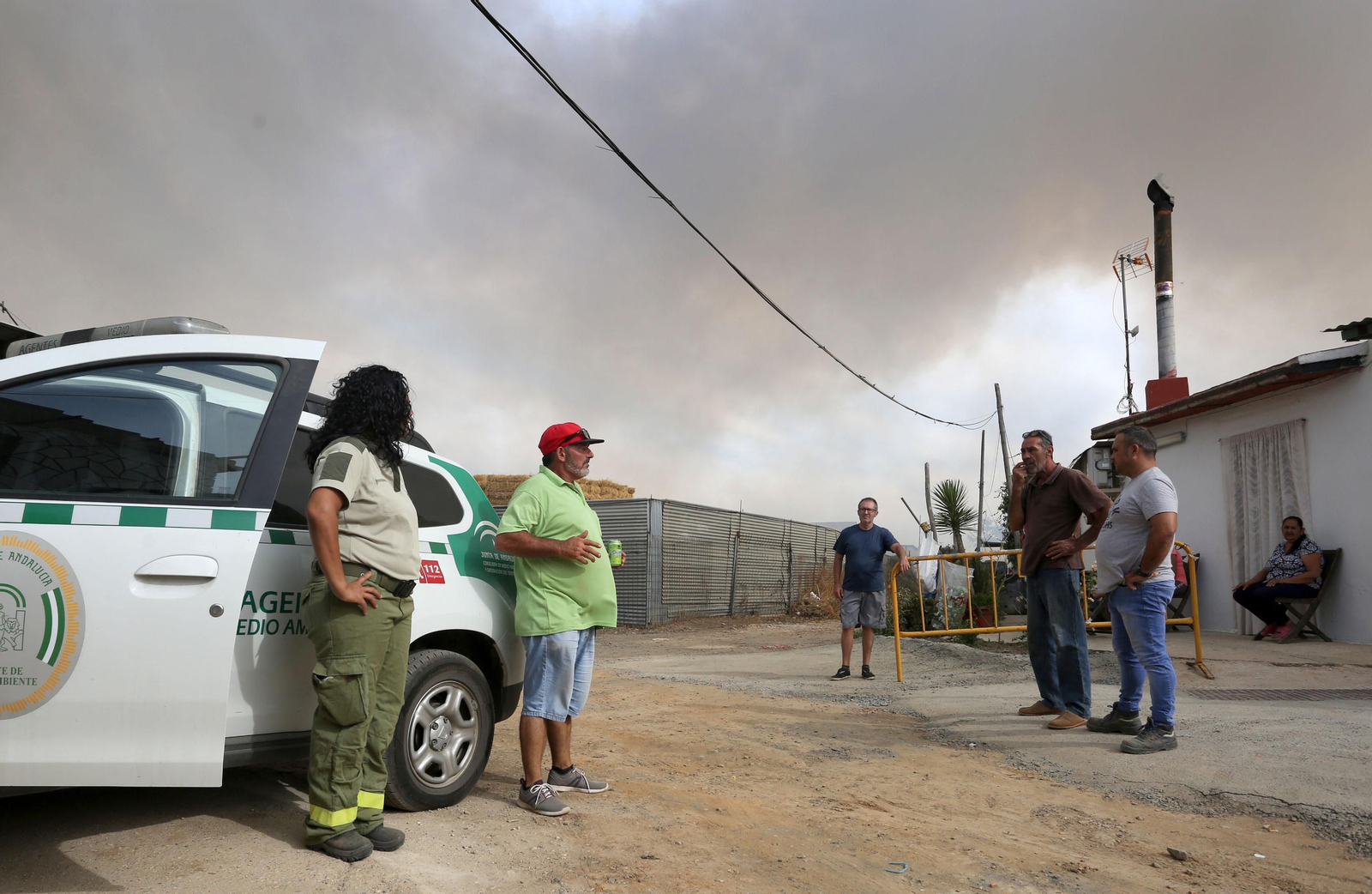 Los vecinos muestran su preocupación a la agente de medio ambiente, con la humareda de fondo.