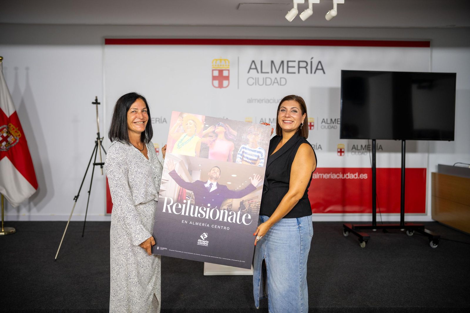 Carmen Sánchez y Lorena Nieto, con el cartel promocional de las compras en el centro de la ciudad