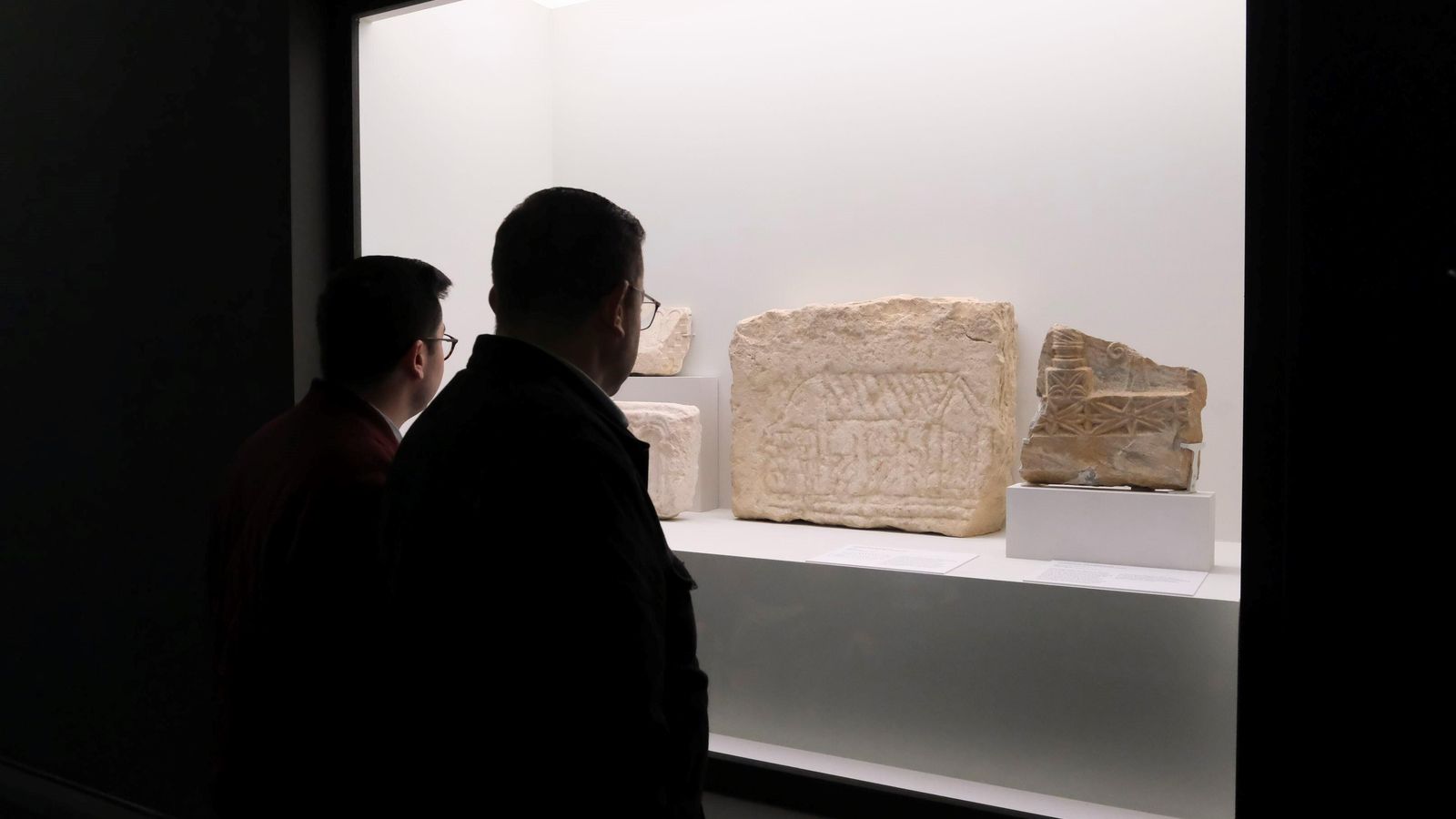 Dos personas observan las piezas expuestas.