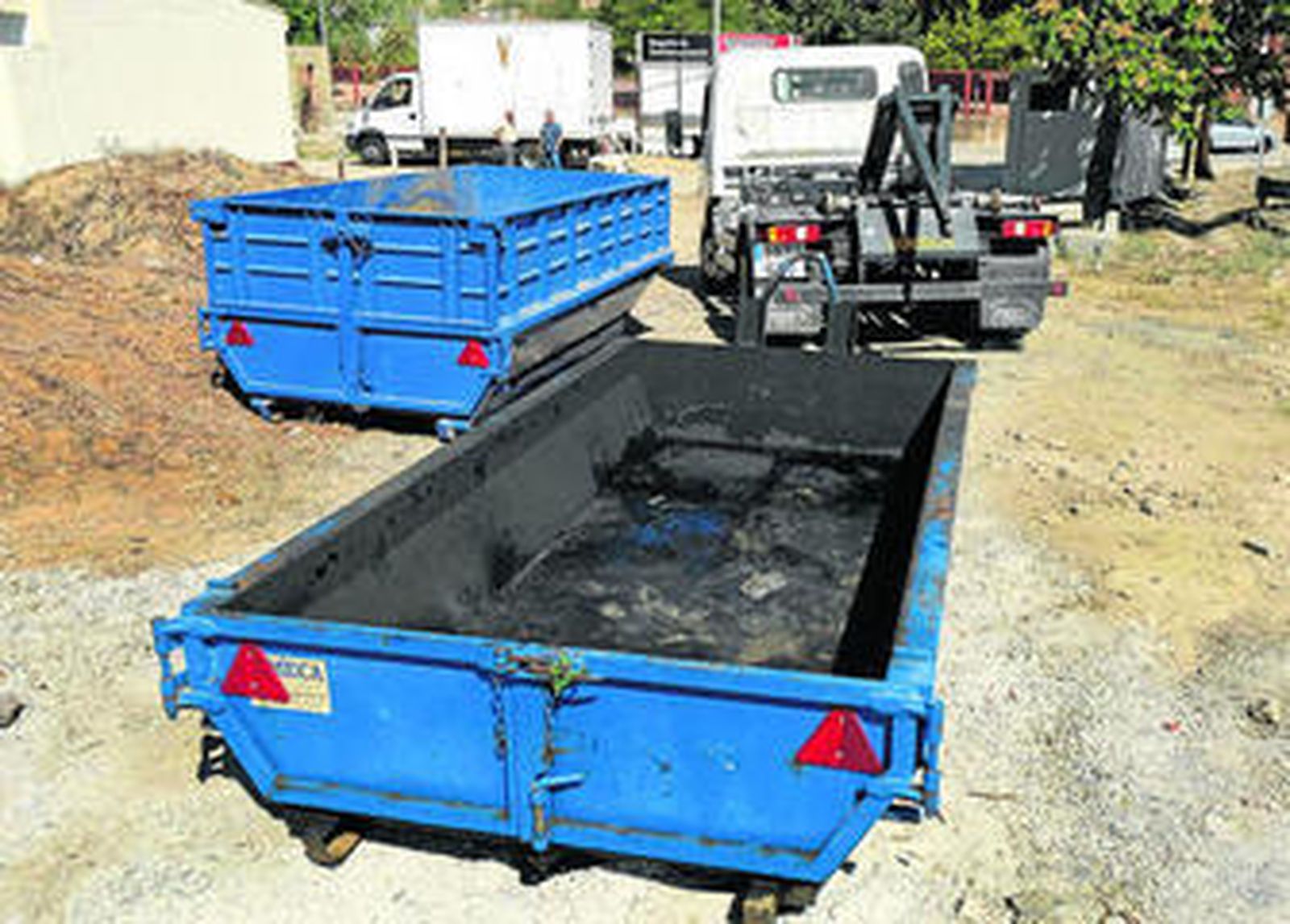 Una grúa se dispone a retirar el contenedor de residuos en el que fue encontrado el cadáver carbonizado de la mujer.