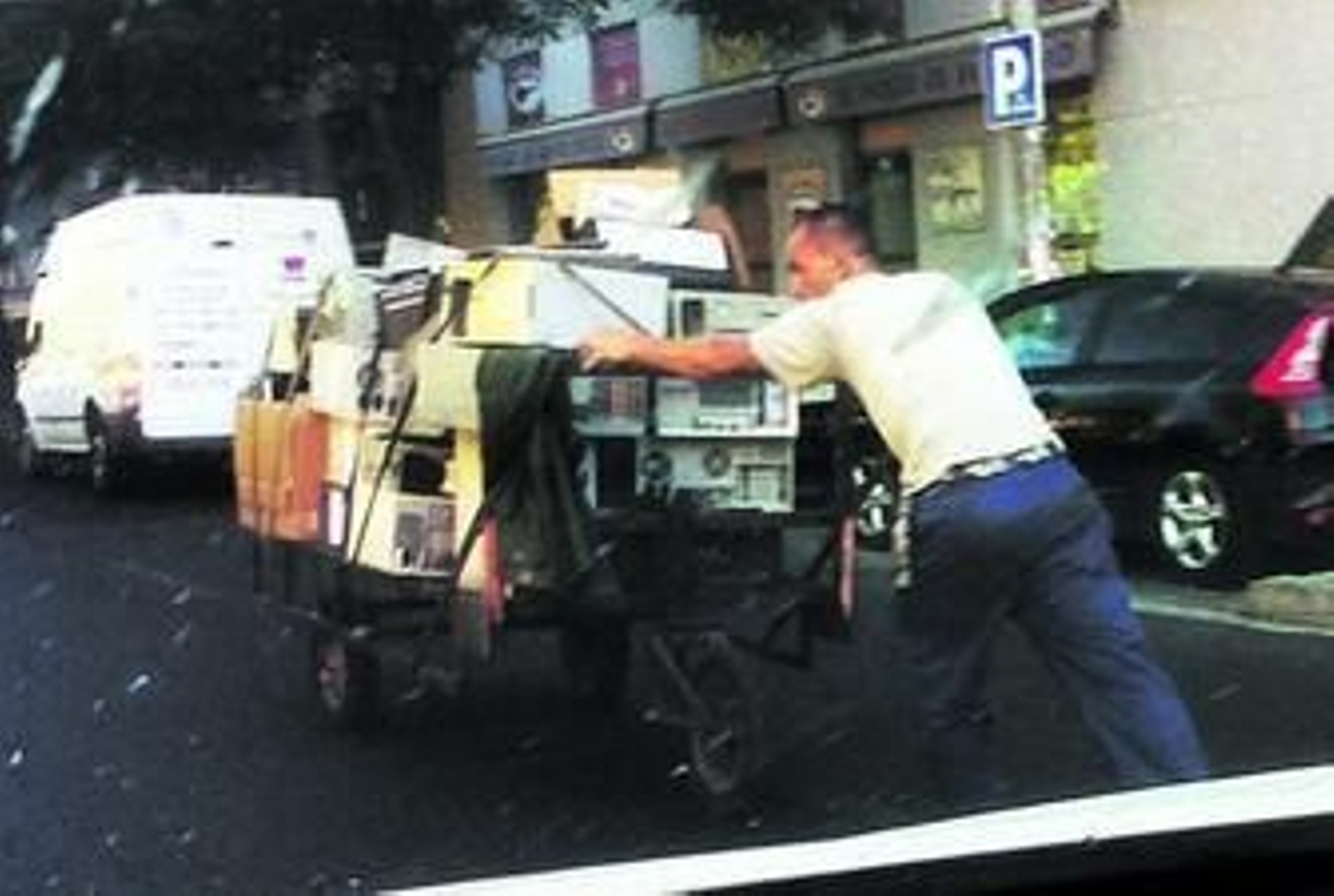 Un hombre tira de un carro repleto de productos eléctricos.