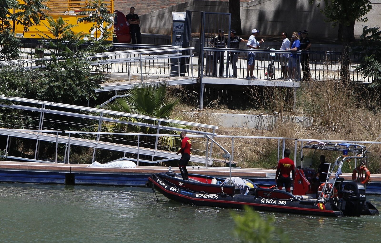 Los Bomberos trabajan en su embarcación, con el cuerpo cubierto en el pantalán.