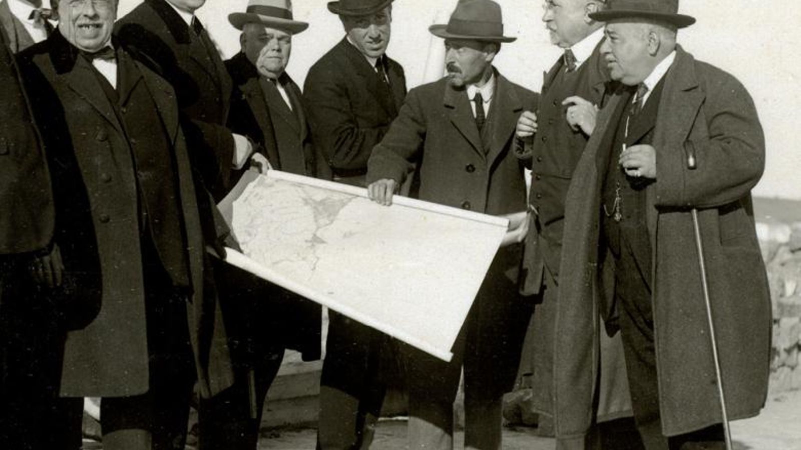 Visita del Director General de Obras Públicas, señor Azqueta, al puerto. Entre las autoridades se encuentran, además del Director General, el Presidente de la Junta de Obras y el diputado José Luis de Torres, que reciben las explicaciones del proyecto del Rompeolas de la Isla Verde del Ingeniero Director, Cástor Rodríguez del Valle. Enero de 1919