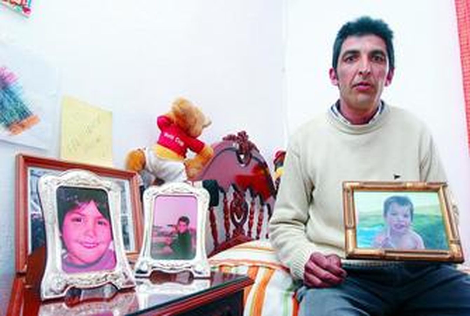 José Luis Contreras posa con fotos de sus hijos, que viven en una casa de acogida en Alemania.