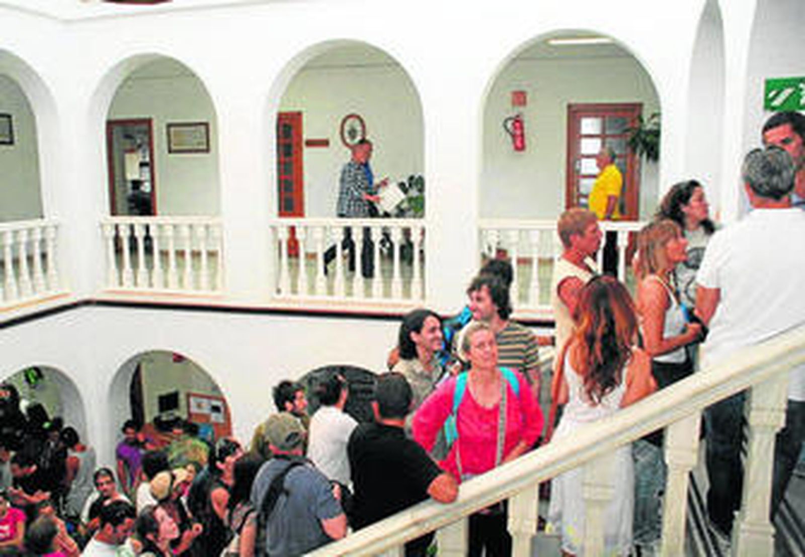 El alcalde se dirige junto a otro edil por la galería al salón de plenos entre protestas en el interior del Consistorio.