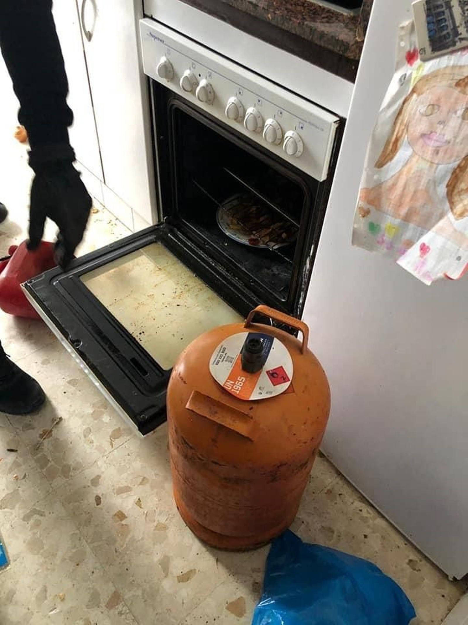 Imagen de la bombona de butano junto al horno con la intención de explosionar la vivienda.