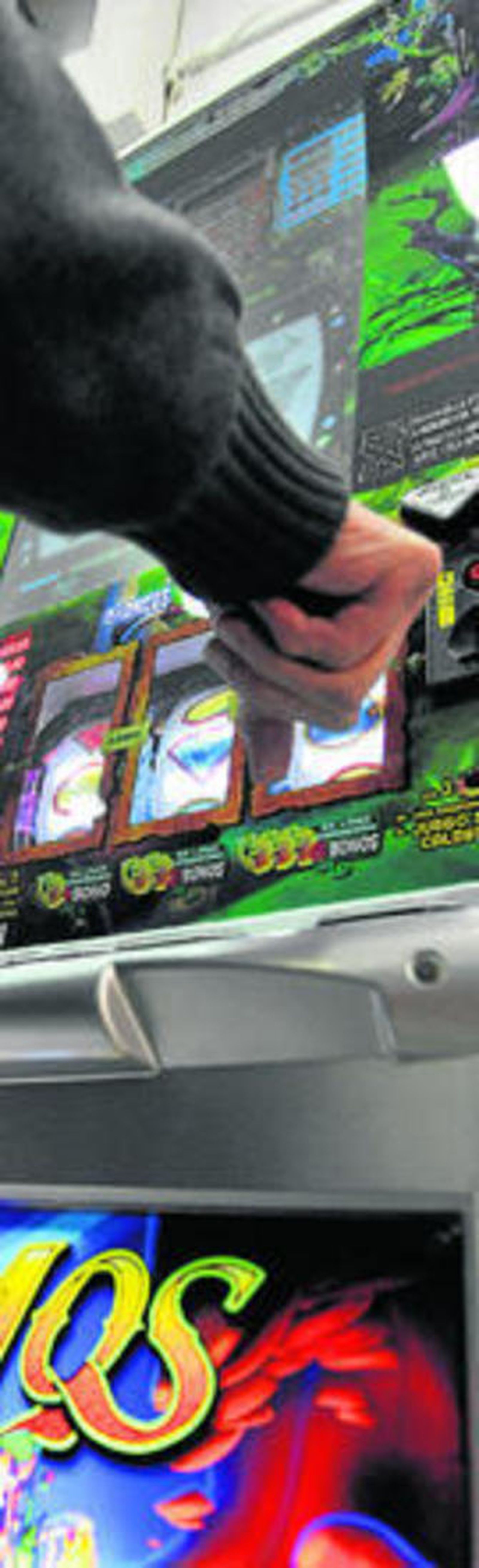 Un hombre apostando en una máquina de azar en un establecimiento.