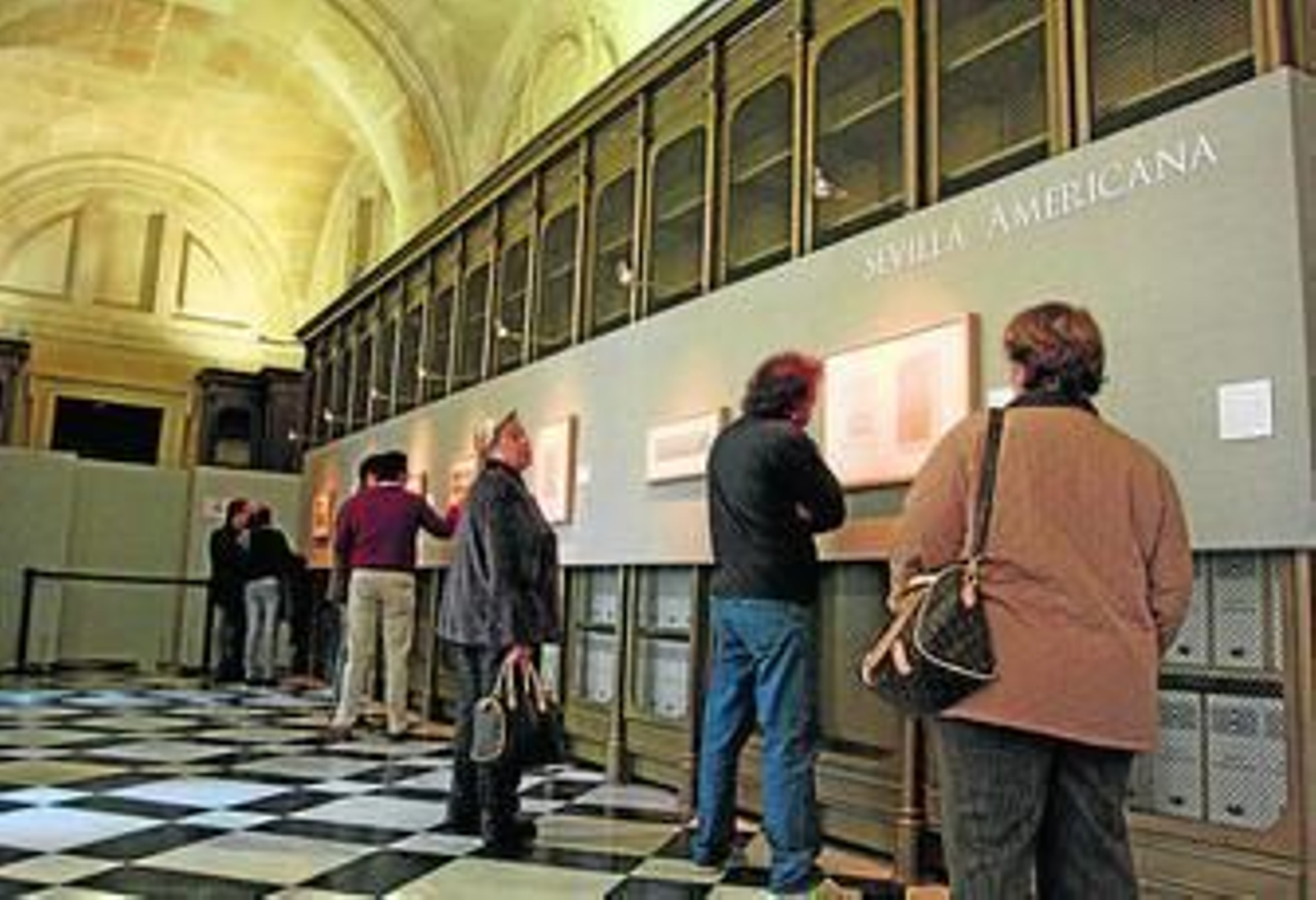 1. Los visitantes observan varios grabados de paisajes de la muestra 'Sevilla Americana'. 2. El cañón del galeón 'Nuestra Señora de Atocha', en la planta baja del edificio . 3. Un hombre observa una réplica de las tres carabelas que descubrieron América. 4. El comisario Manuel Álvarez detalla una portada del 'The Illustrated London News' sobre la tumba de Cristóbal Colón.