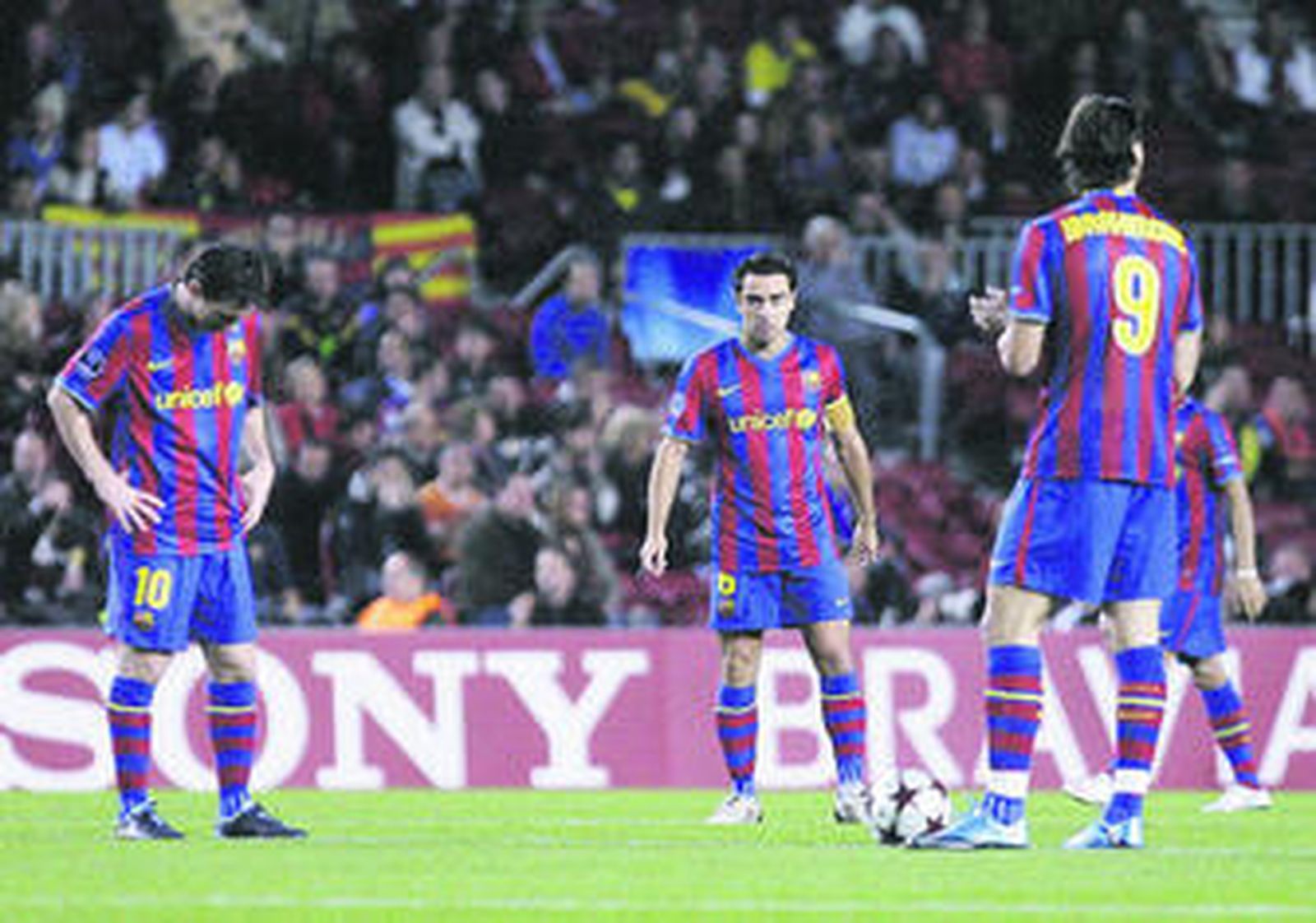 Xavi mira a Messi, cabizbajo, a la espera de sacar de centro tras uno de los goles del Rubin Kazan.