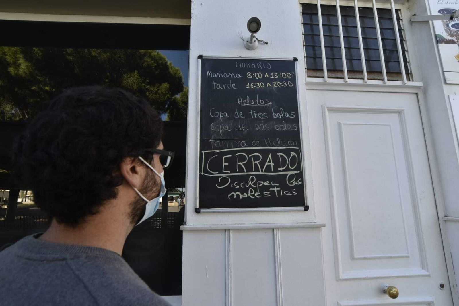 Una persona observa el cartel que anuncia el cierre de la cafetería Plum Cake, en San Roque.