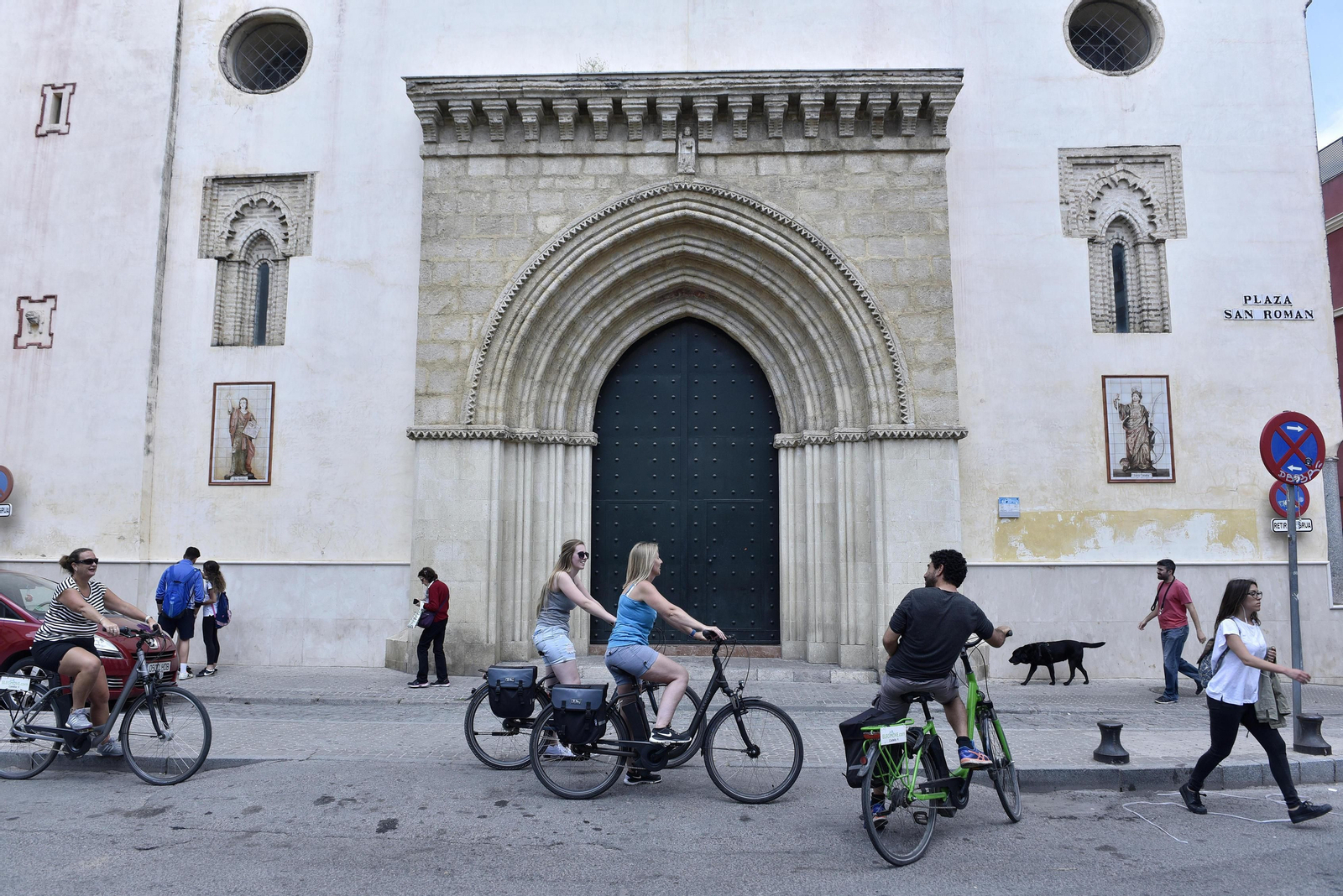 Peatones, ciclistas y un vehículo coinciden en la puerta principal de la iglesia de San Román.