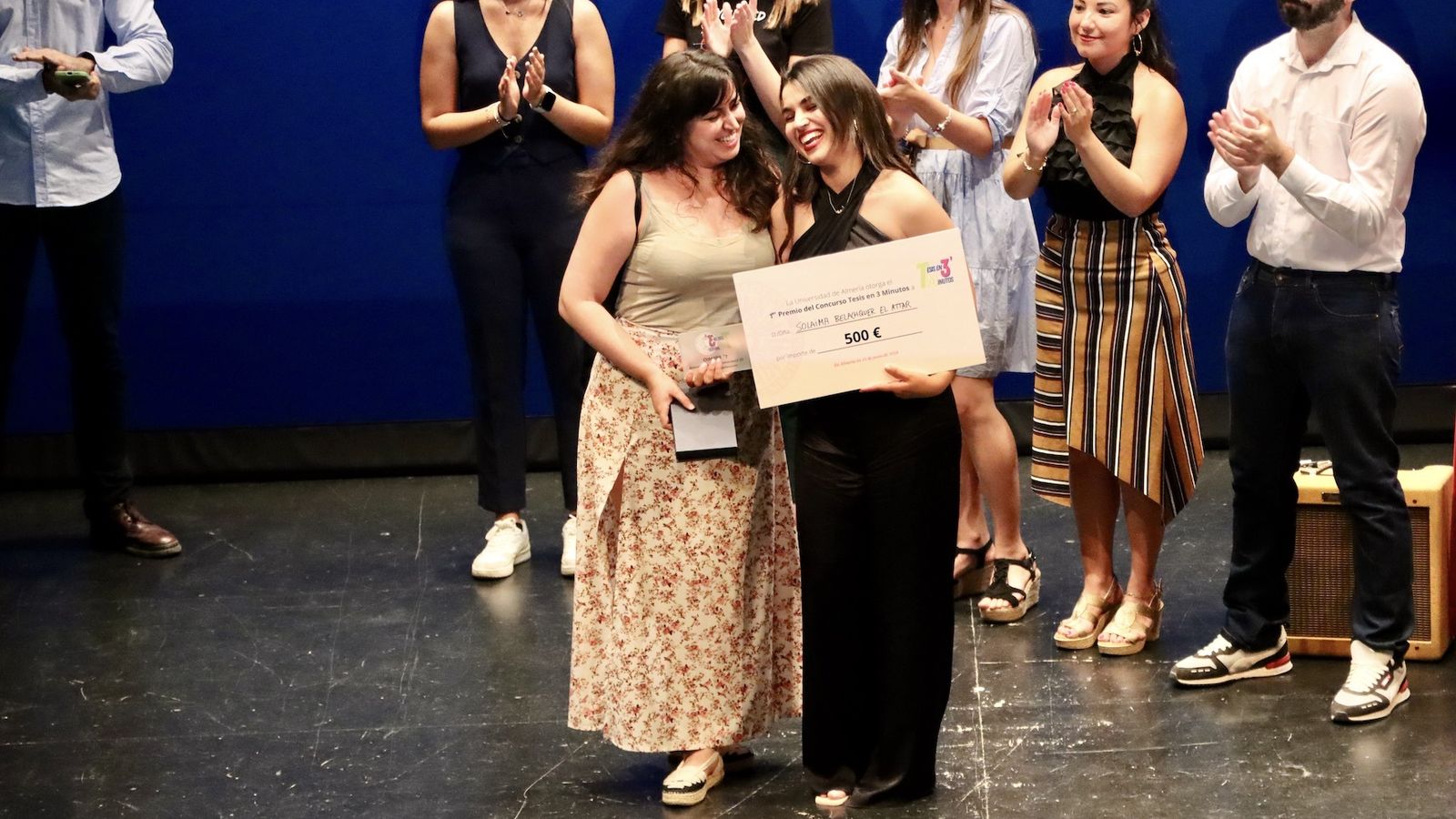 La ganadora de ‘Tesis en 3 minutos’, Solaima Belachqer, recibe su premio de manos de la portavoz del jurado, en el escenario del Teatro Apolo.